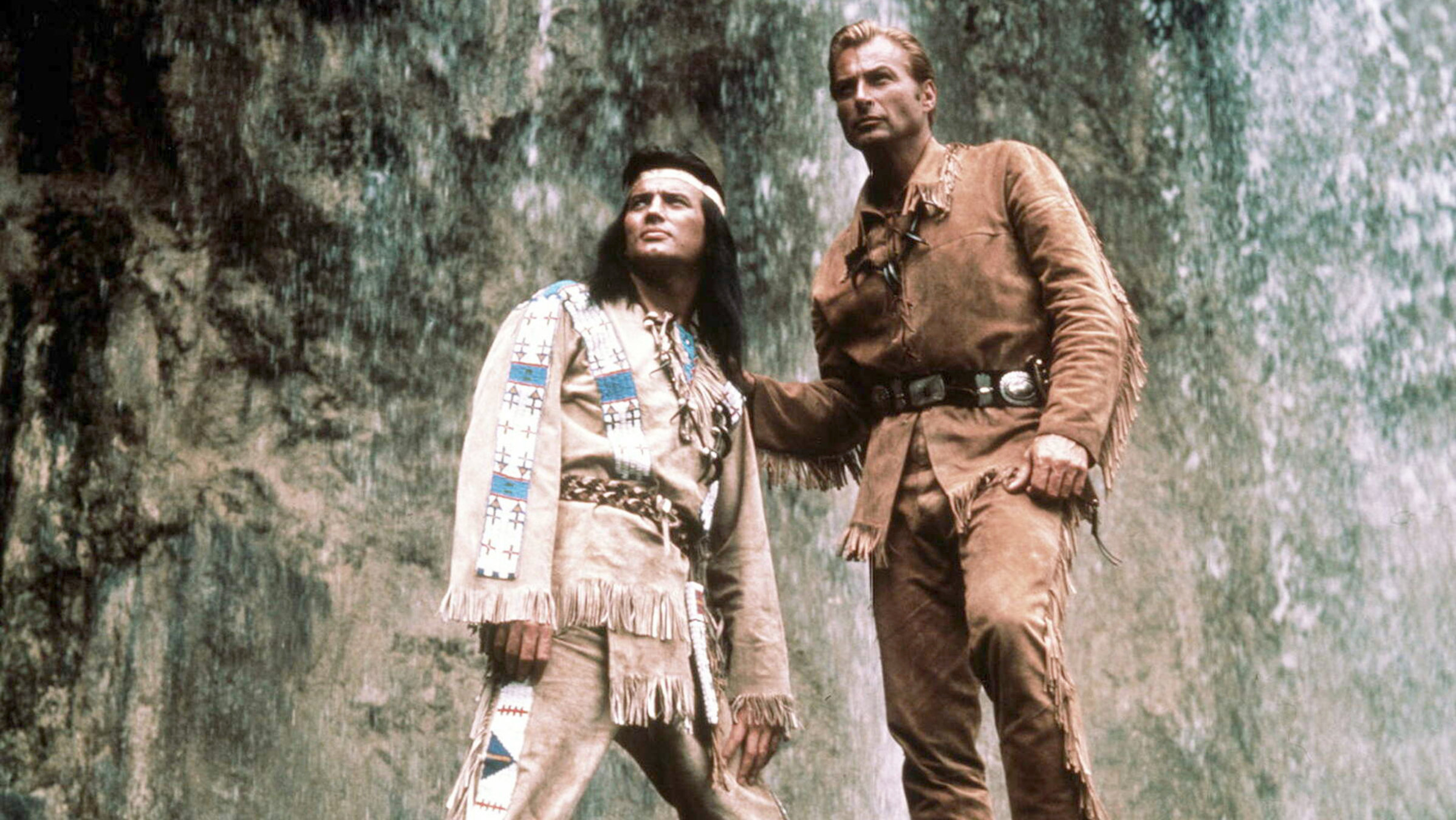 "Der Schatz im Silbersee": Winnetou (Pierre Brice) und Old Shatterhand (Lex Barker) stehen vor einem Wasserfall und schauen in die gleiche Richtung.