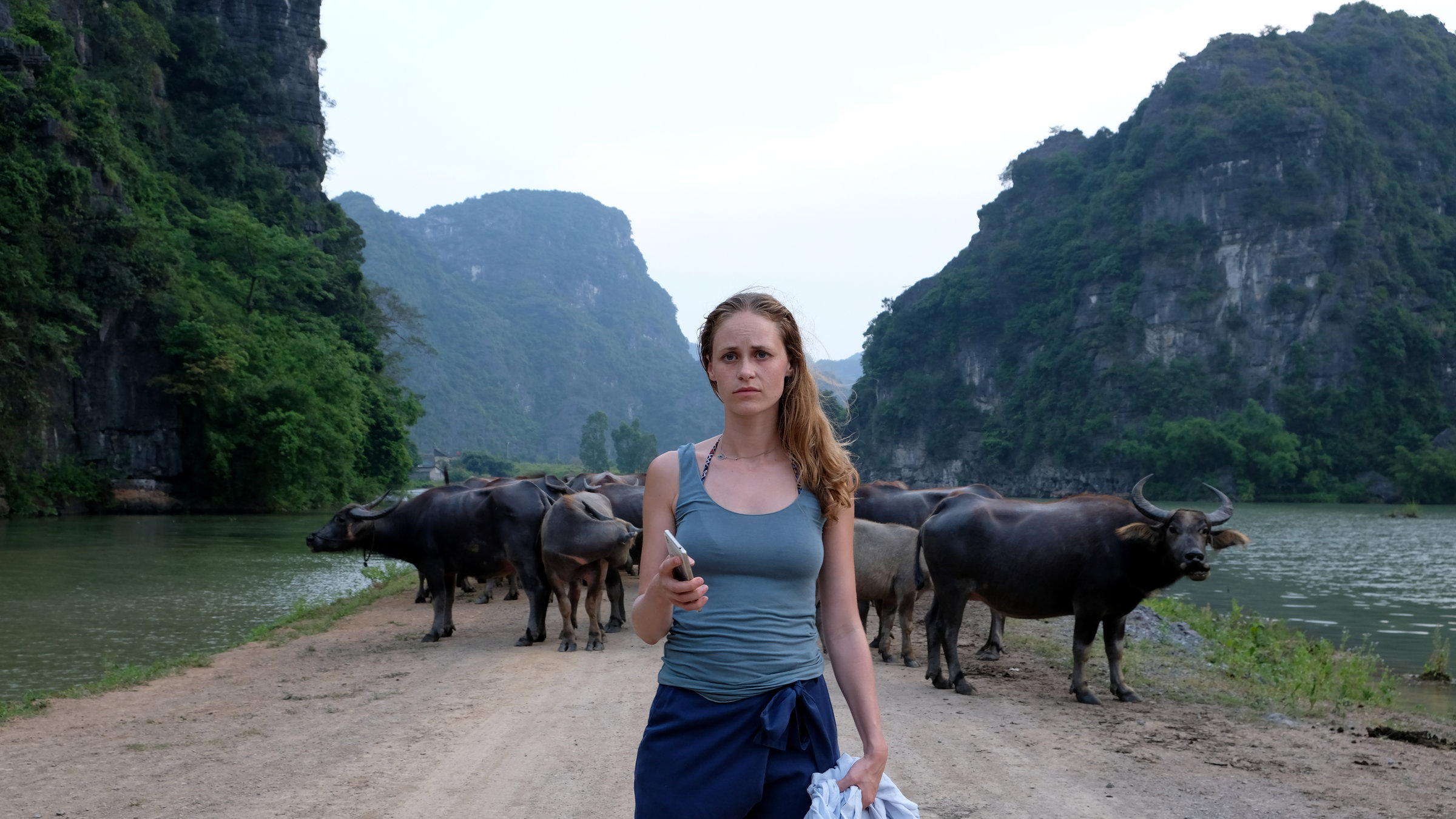 "Ein Sommer in Vietnam": Vor einer Herde Kühe läuft Paula (Inez Bjørg David) auf einem Weg, der von Bergen und Wasser eingerahmt ist.