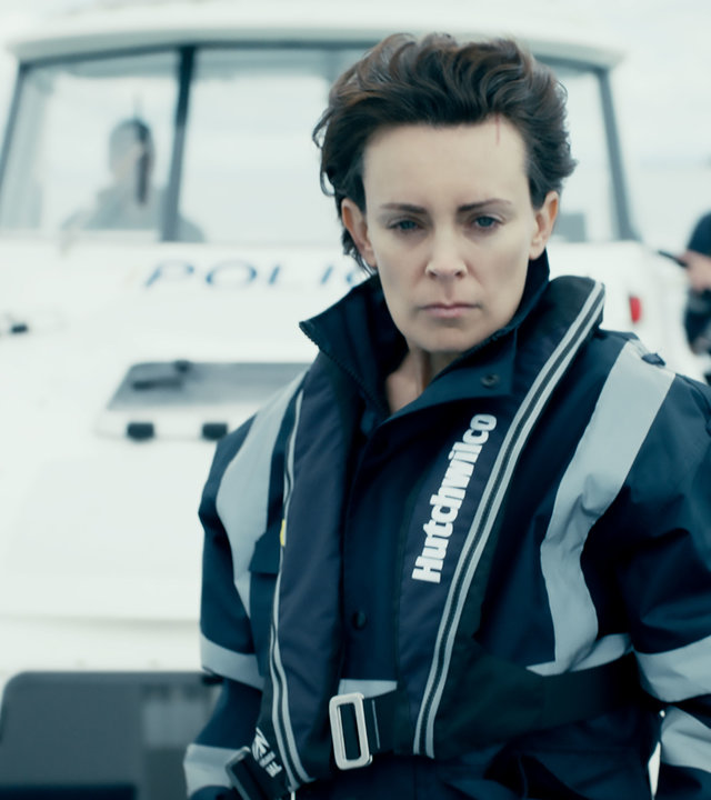 "Auckland Detectives  - Tödliche Bucht / Spurlos": Detective Senior Sergeant Jessica Savage (Kate Elliott) steht in wasserabweisender Polizeikleidung auf dem Deck eines Polizeibootes und schaut entschlossen nach vorn. Im Hintergrund stehen zwei weitere Polizisten (Darsteller unbekannt).