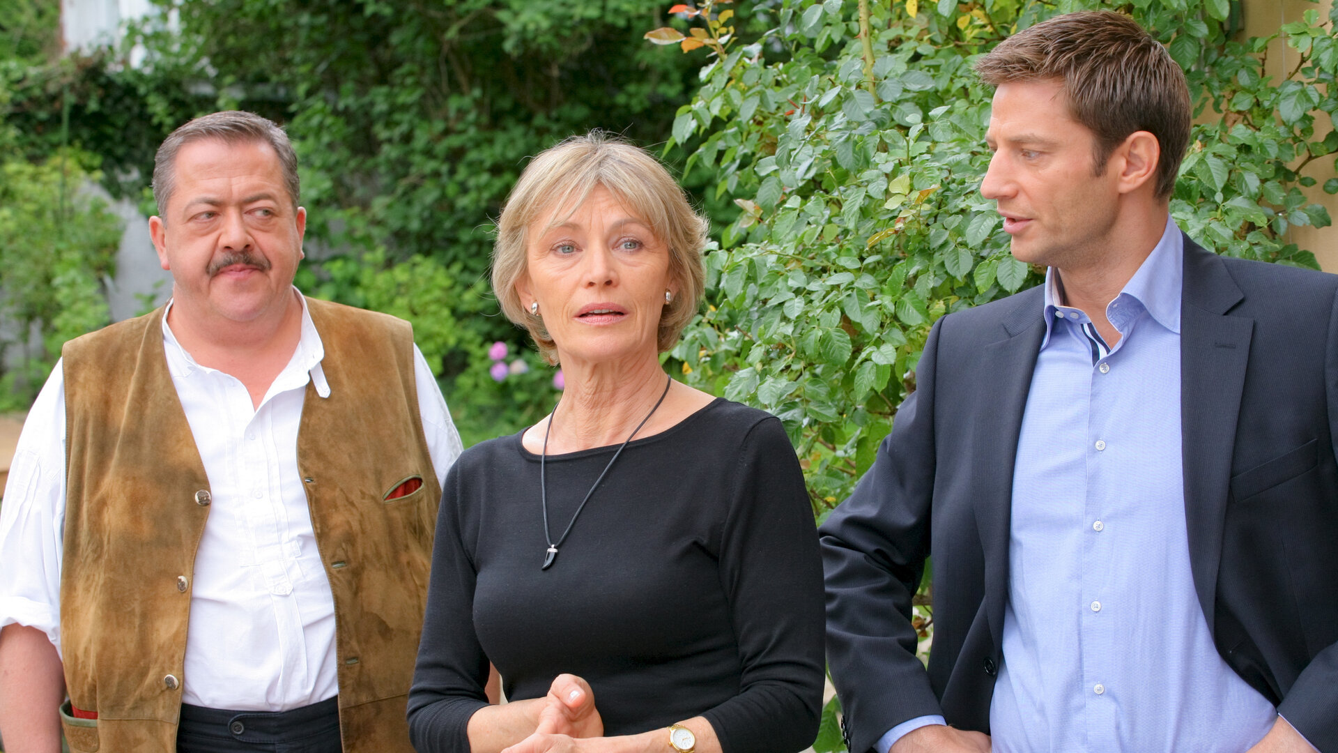 "Die Rosenheim-Cops - Mörderische Rache": Vor dem Haus befragen die Kommissare Korbinian Hofer (Joseph Hannesschläger) und Sven Hansen (Igor Jeftic) Sabine Giese (Ilona Grübel).
