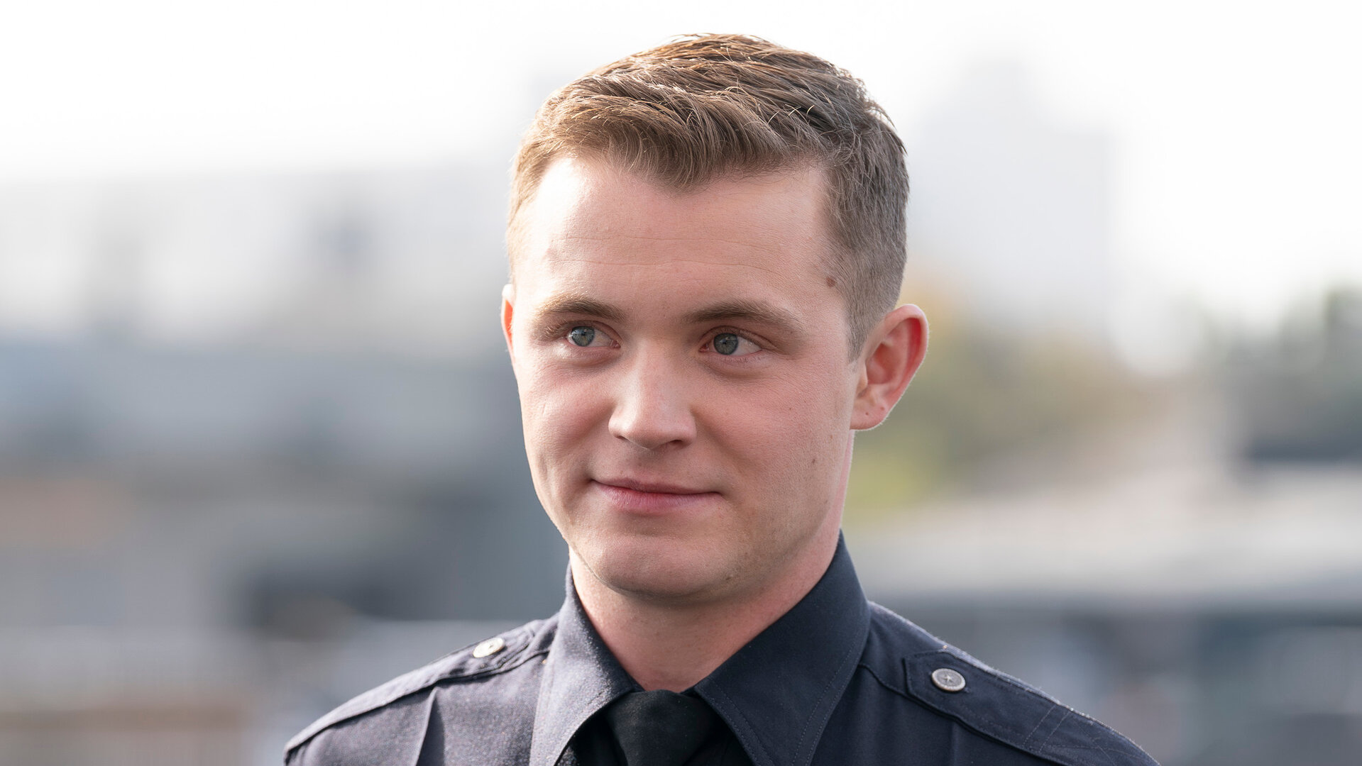 "The Rookie - Die Rückkehr": Draußen auf einem Gelände steht Rookie Seth Ridley (Patrick Keleher) und blickt nach vorn. Er trägt eine dunkle Polizeiuniform