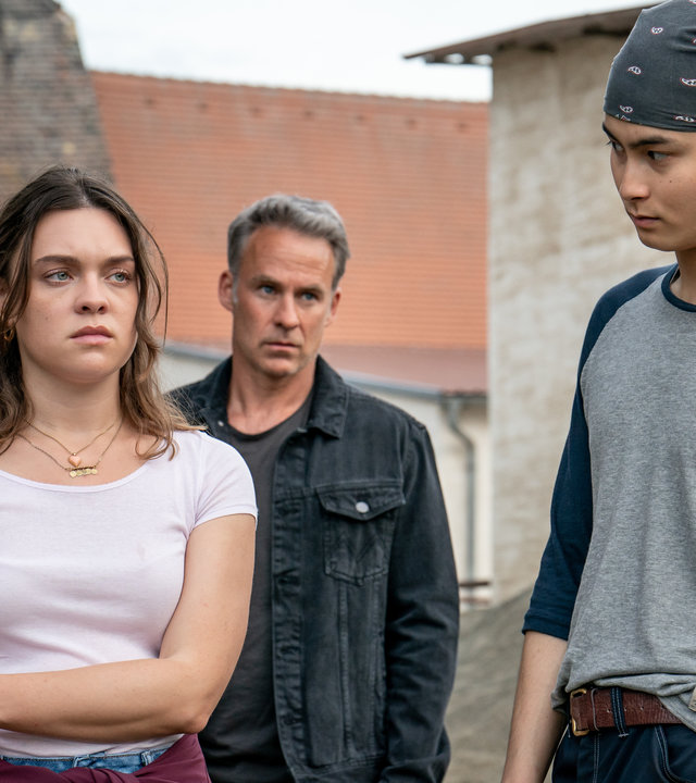 "SOKO Leipzig - Das Leben ist kein Ponyhof": Carina Zadek (Amelie Hennig) steht neben Timo Rönow (Anand Batbileg Chuluunbaatar) und schaut mit traurigem Blick in Richtung Timo. Er schaut sie wiederum betroffen an. Hinter den beiden steht Jan Maybach (Marco Girnth) und beobachtet die Reaktionen der beiden.