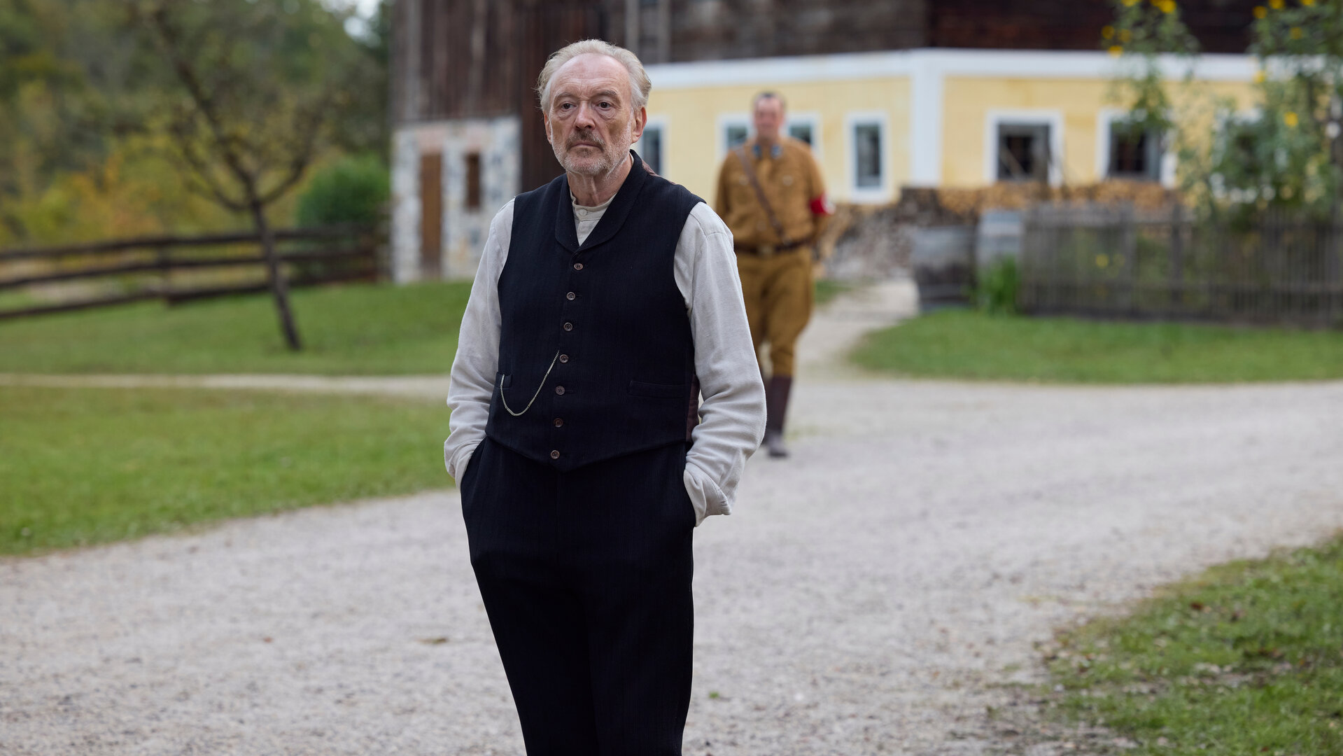 "Sturm kommt auf": Der Schuster Julius Kraus (Josef Hader) steht vor dem Heingeiger Hof, hinter ihm steht Silvan (Sigi Zimmerschied) in SA-Uniform.