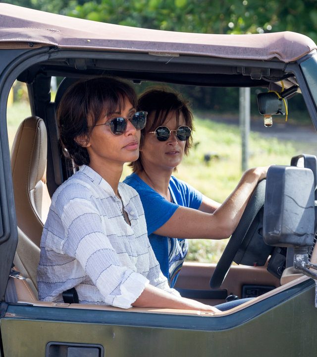 "Deadly Tropics - Mörder oder Mythos?": Sainte-Rose (Sonia Rolland) und Crivelli (Béatrice de la Boulaye) sitzen nebeneinander in einem Geländewagen und schauen unbeeindruckt zur Seite.