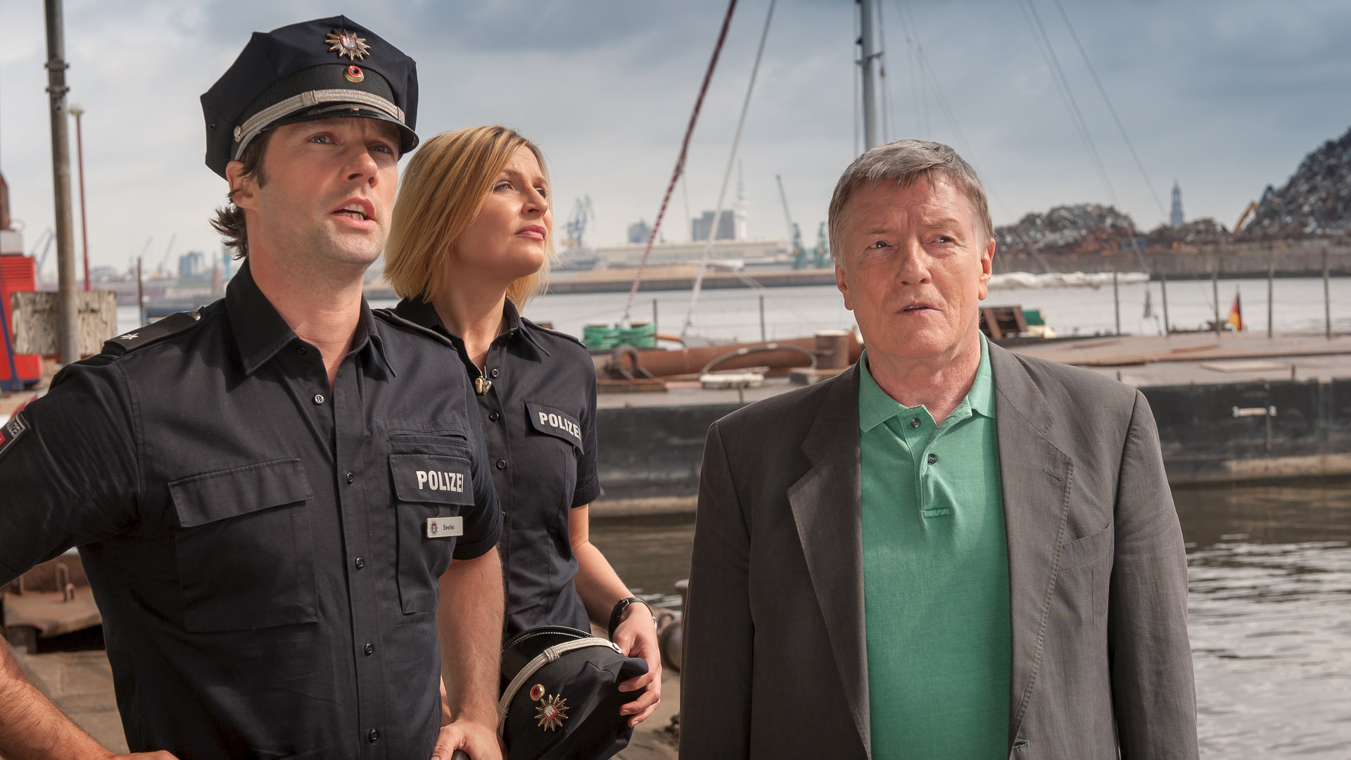 "Notruf Hafenkante - Abgetaucht": Mattes (Matthias Schloo) und Melanie (Sanna Englund) stehen mit Werner Grün (Manfred Zapatka) am Hafen. Sie schauen alle in die gleiche Richtung.