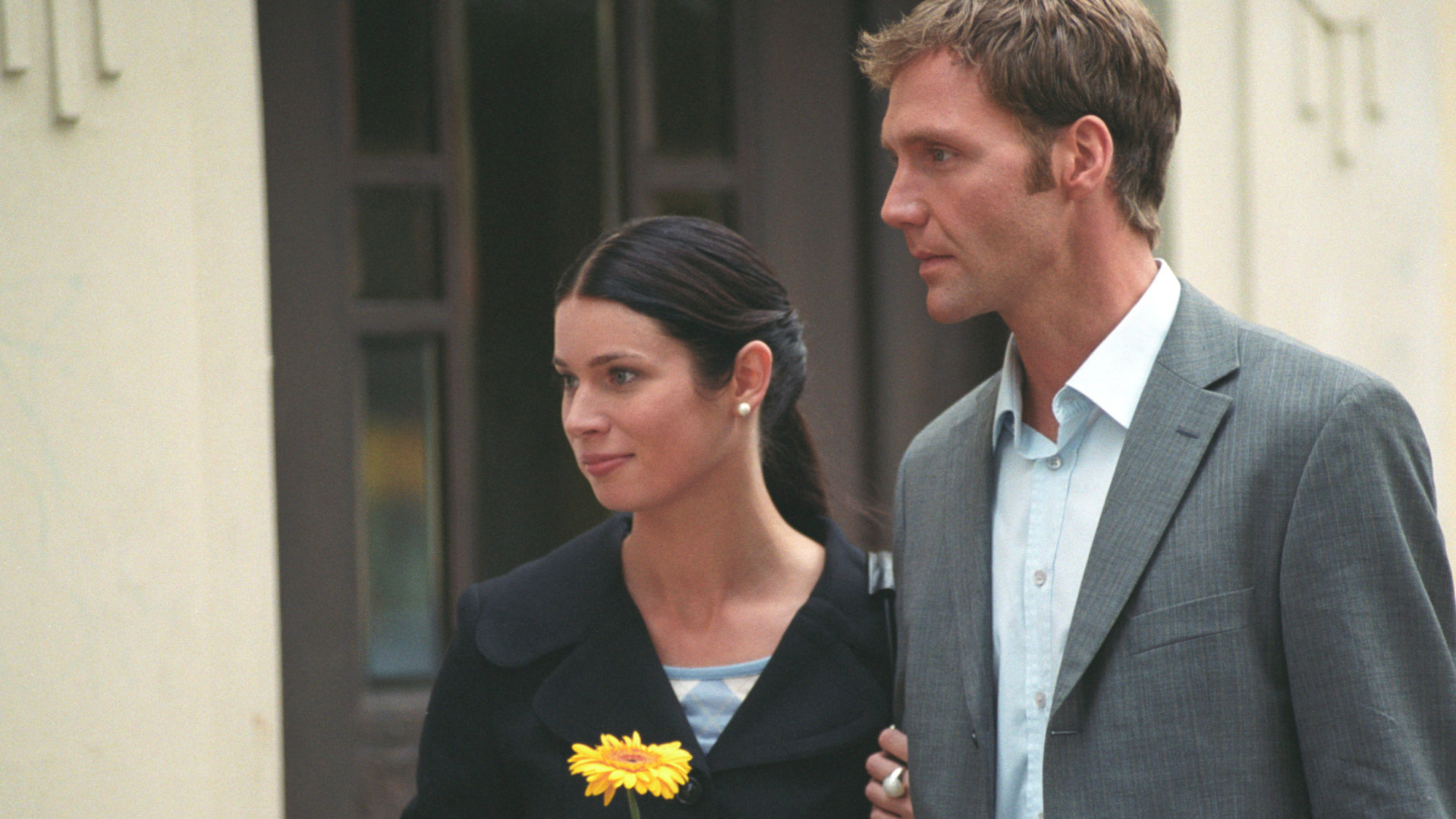 "Bianca - Wege zum Glück: Folge 34": Vor dem Gutshof: Judith (Elisabeth Sutterlüty) und Oliver (Patrick Fichte) stehen als Paar nebeneinander. Judith hält eine gelbe Margerite in der Hand und schaut freundlich nach rechts. Oliver wirkt verzweifelt.