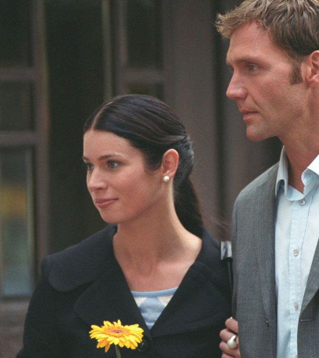 "Bianca - Wege zum Glück: Folge 34": Vor dem Gutshof: Judith (Elisabeth Sutterlüty) und Oliver (Patrick Fichte) stehen als Paar nebeneinander. Judith hält eine gelbe Margerite in der Hand und schaut freundlich nach rechts. Oliver wirkt verzweifelt.
