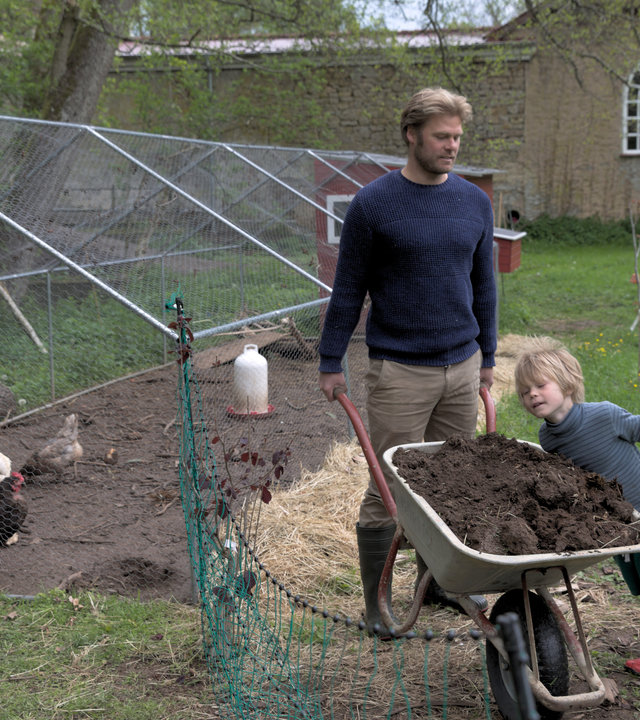 "37° Unsere eigene Farm - Selbstversorgen lernen": Michael und Sara stehen ihrem kleinen Sohn Max und einer Schubkarre, gefüllt mit Erde, neben dem Außengehege eines Hühnerstalls. Man sieht auch weiße und braune Hühner.