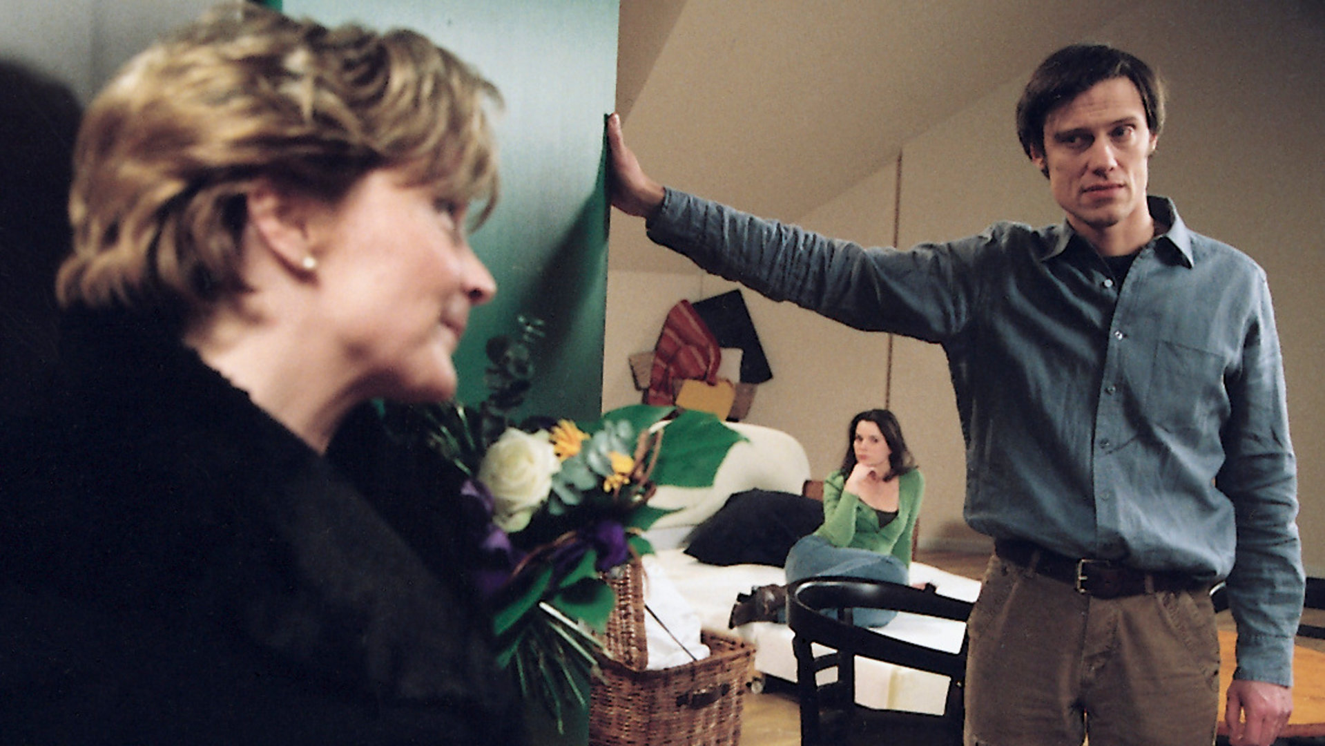 "Bianca - Wege zum Glück: Kapitel 131":  Vor einer Wohnungstür: Ariane (Kerstin Gähte) steht mit einem Blumenstrauß vor Matthias (Andreas Hutzel) Wohnungstür. Matthias hält die Tür auf und im Hintergrund sitzt Tina (Eva Klemt) auf einer hellen Couch. Matthias wirkt überrascht.