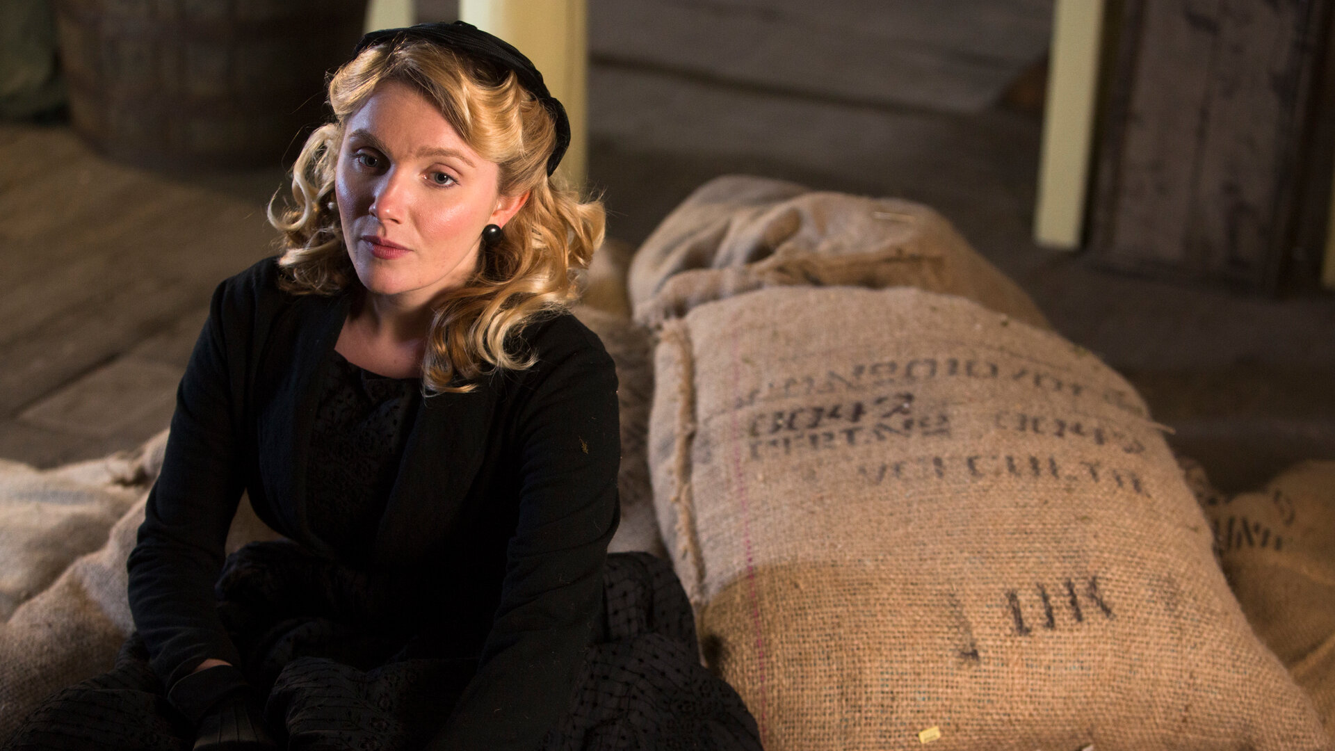 "Father Brown - Die Tochter des Brauers": Grace Fitzgerald (Rosemary Boyle) sitzt in einer Scheune auf großen Jutesäcken. .