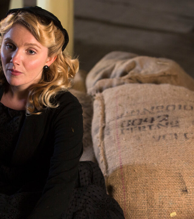 "Father Brown - Die Tochter des Brauers": Grace Fitzgerald (Rosemary Boyle) sitzt in einer Scheune auf großen Jutesäcken. .
