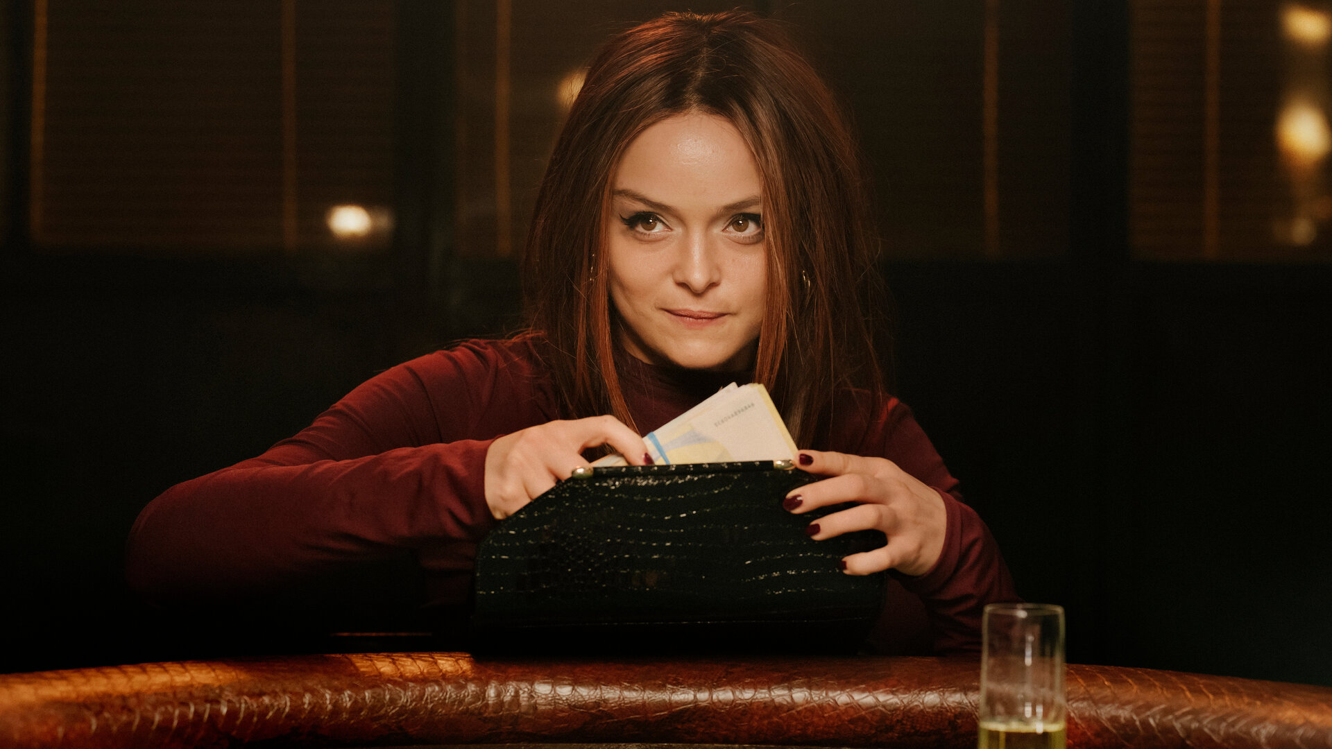 "High Stakes - Ayla vs. Nina": Ayla (Via Jikeli) sitzt am Pokertisch und holt Geld aus ihrer Handtasche.