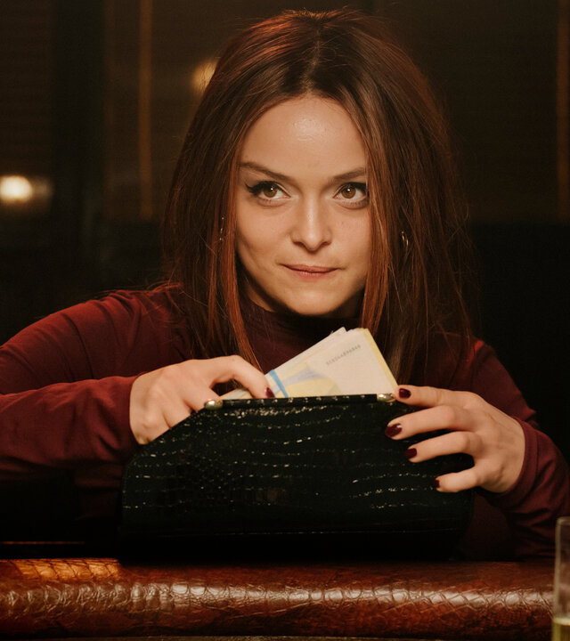 "High Stakes - Ayla vs. Nina": Ayla (Via Jikeli) sitzt am Pokertisch und holt Geld aus ihrer Handtasche.