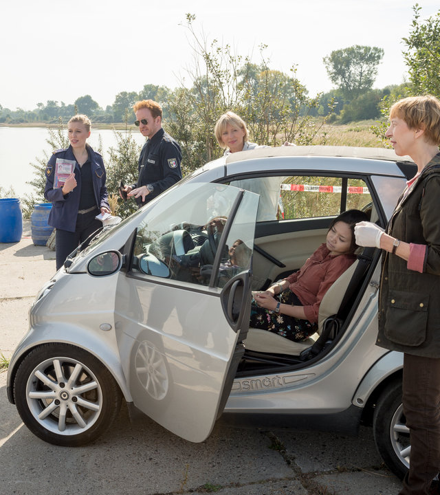 "SOKO Wismar – Eisbärchen“: Auf einem asphaltierten Gelände stehen Katrin Börensen (Claudia Schmutzler), Lars Pöhlmann (Dominic Boeer), Anneke van der Meer (Isabel Berghout), Kai Timmermann (Mathias Junge) und Dr. Helene Sturbeck (Katharina Blaschke) um ein Auto herum, in dem die Leiche von Araya Müller (Komparsin) ist.