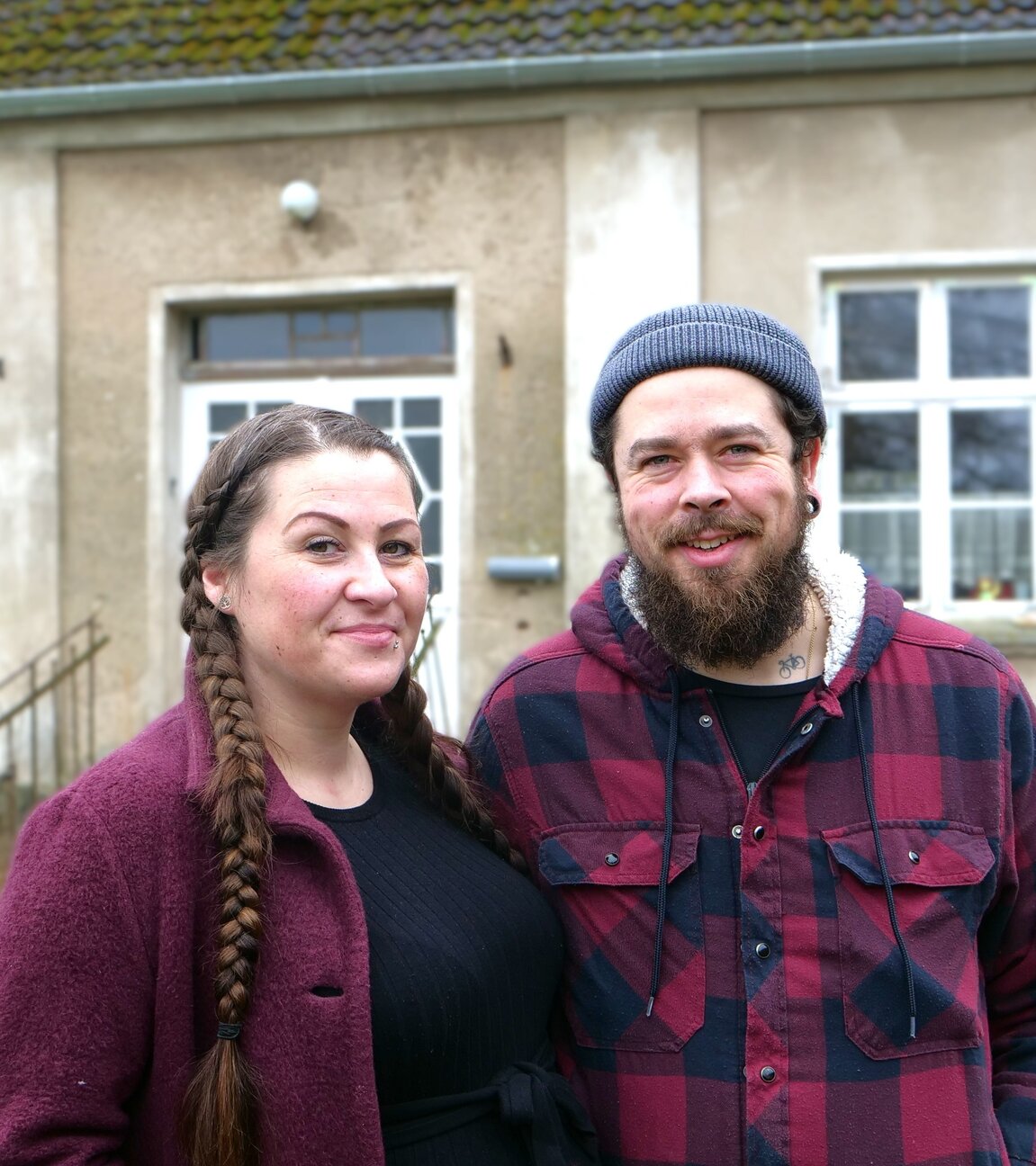 "ZDF.reportage: Großprojekt Hausbau": Sara und Max stehen nebeneinander vor einem alten Haus und blicken lächelnd in die Kamera.