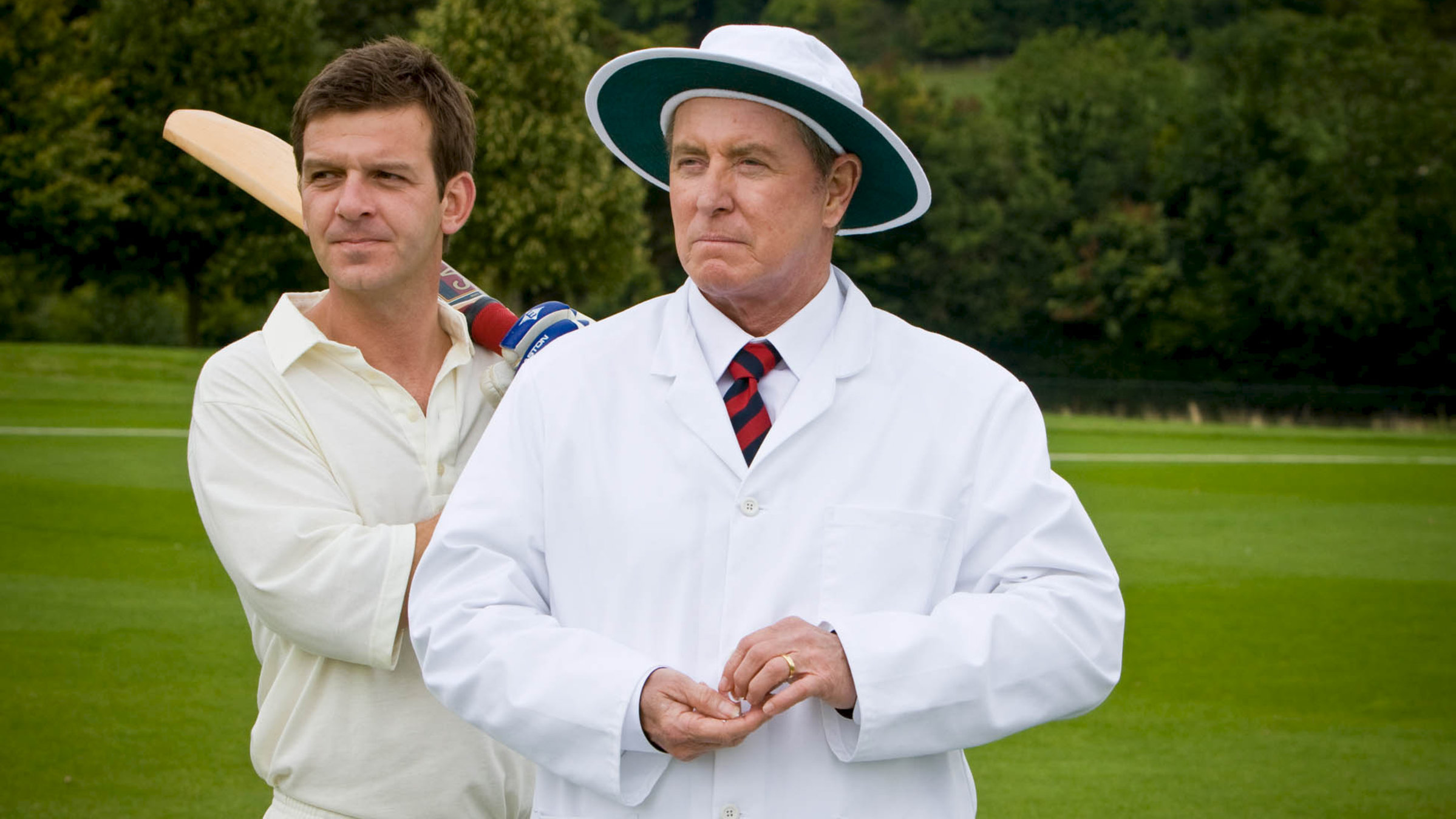 "Inspector Barnaby: Sportler und Spione": Außenaufnahme auf dem Cricket-Platz - DS Ben Jones (Jason Hughes) und DCI Tom Barnaby (John Nettles) stehen nebeneinander im Cricket-Outfit.