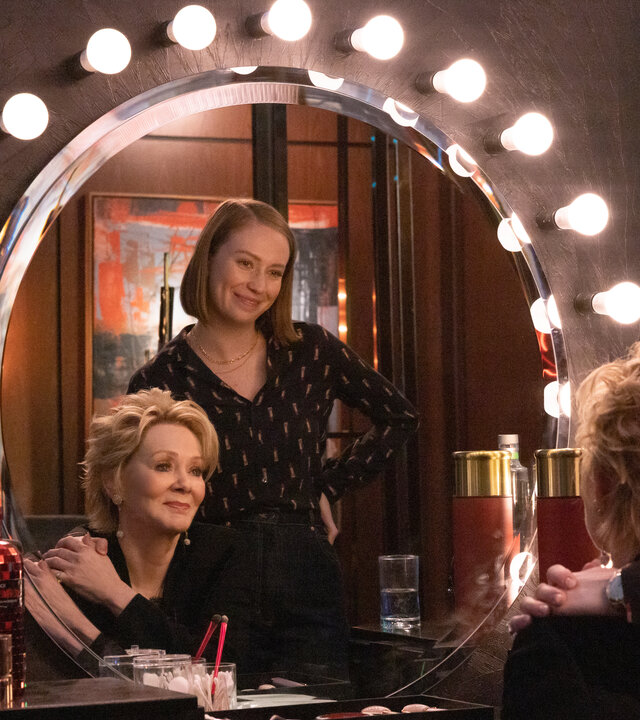"Hacks - Die einzig Wahre(n)": Ava (Hannah Einbinder) steht mit verschränkten Armen hinter Deborah (Jean Smart), die an einem Schminktisch mit einem großen runden Spiegel sitzt, der von zahlreichen Glühbirnen umrahmt ist. Beide blicken zufrieden lächelnd in den Spiegel.