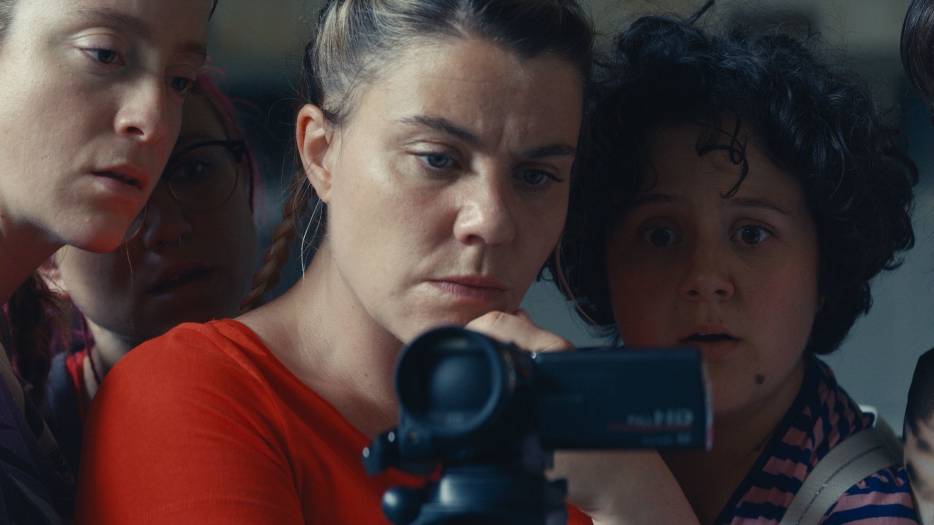 "Derby Girl - Showtime": Mother Blocker (Sophie-Marie Larrouy) hält eine Kamera in ihren Händen. Neben ihr stehen Booby Mercury (Allison Chassagne), Marie-Josée (Salomé Diénis Meulien), Absinthe-ni-touche (Suzanne de Baeque) und Karma (Julia Clavel). Hinter Mother Blocker steht Trash (Adèle Bellanger). Alle Mädchen schauen entsetzt in die Kamera.