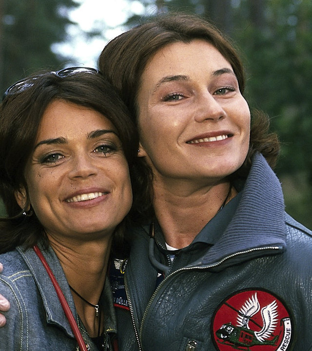 "Die Rettungsflieger - Abschied von Maren": Außenaufnahme im Wald - Maren (Gerit Kling) und Ilona (Julia Heinemann) stehen eng beieinander und strahlen in die Kamera.
