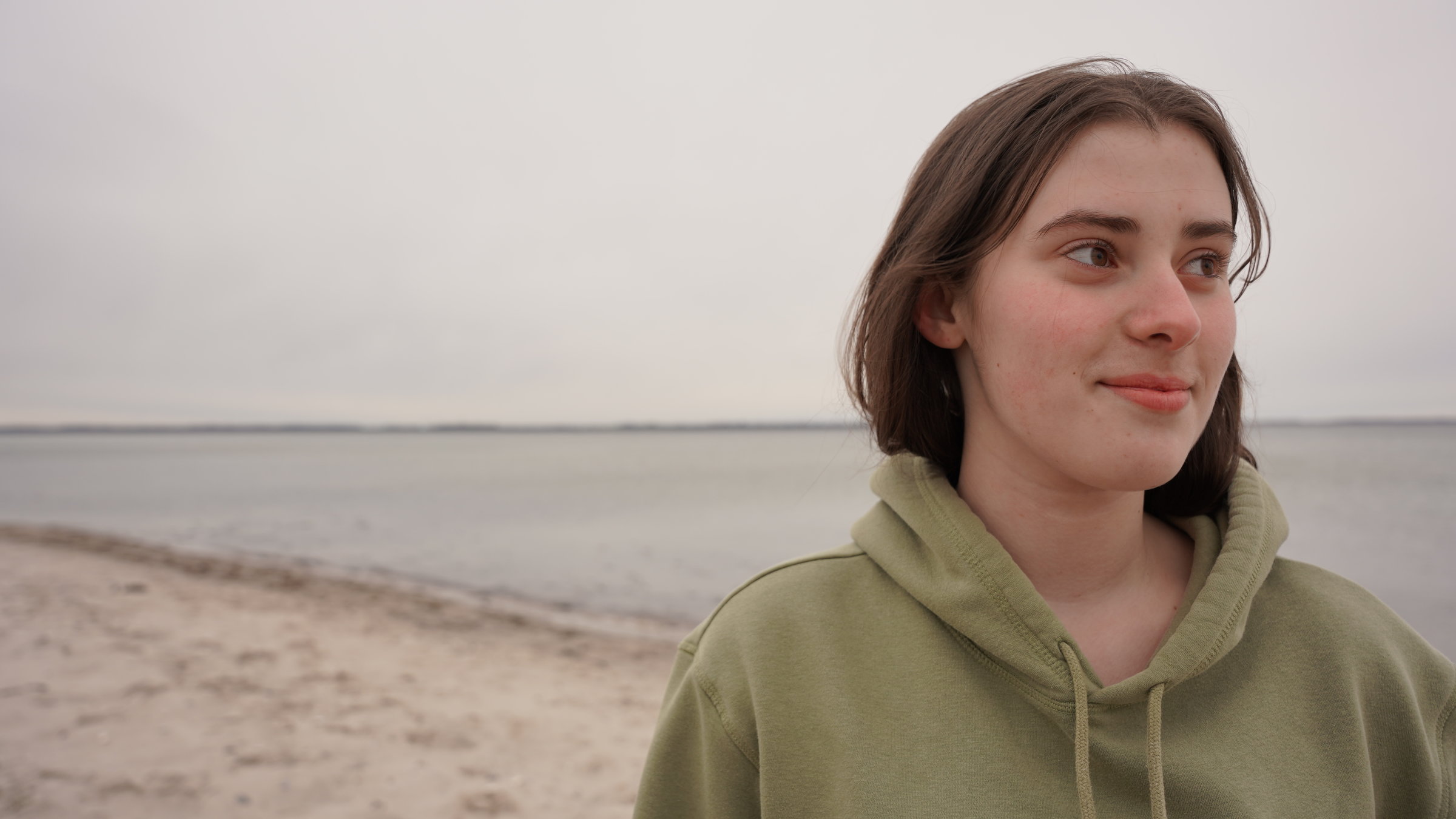 "Jung, begabt und seelisch krank - Wenn jugendliche Hilfe brauchen": Aliya steht am Strand, sie schaut in die Ferne auf das Meer.