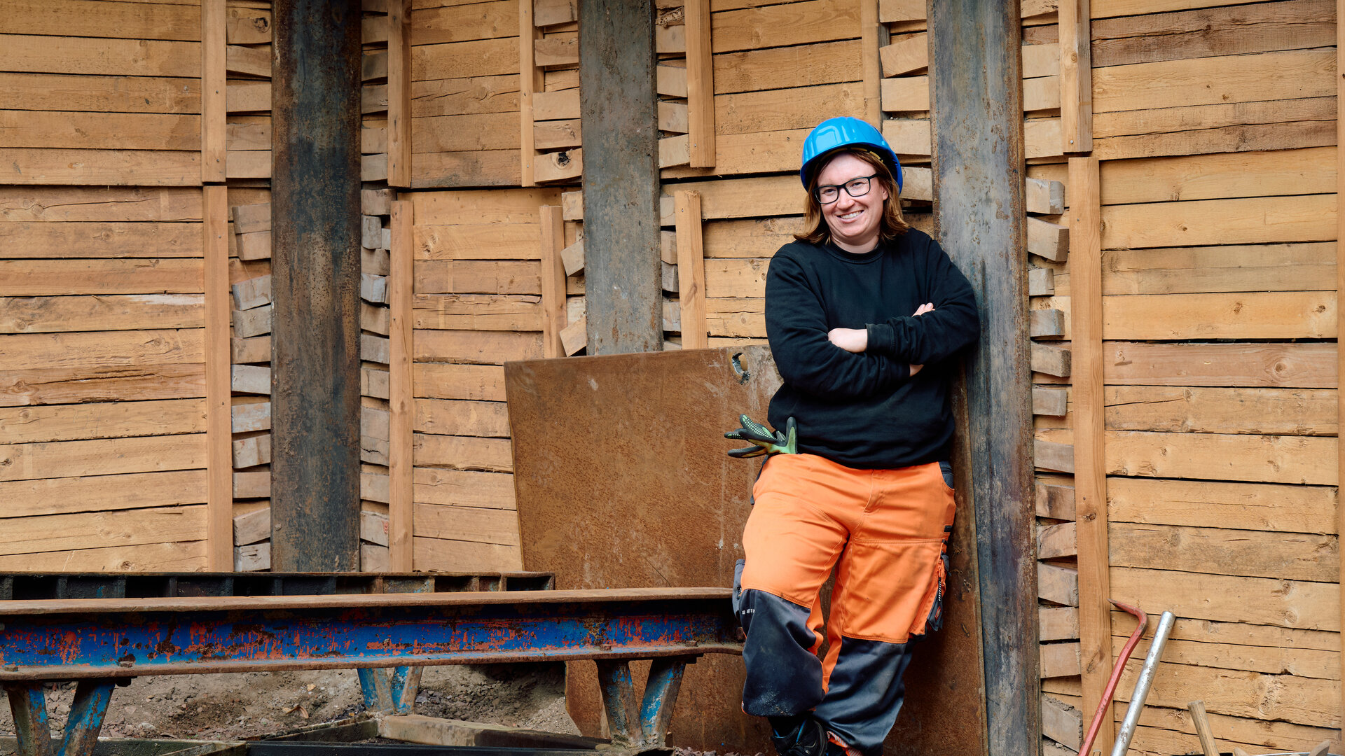 "einfach Mensch - Delia Buchhorn: Grenzt mich nicht aus": Delia Buchhorn steht in Schutzkleidung mit Helm auf einer Baustelle vor einer Holzwand und schaut lächelnd in die Kamera.