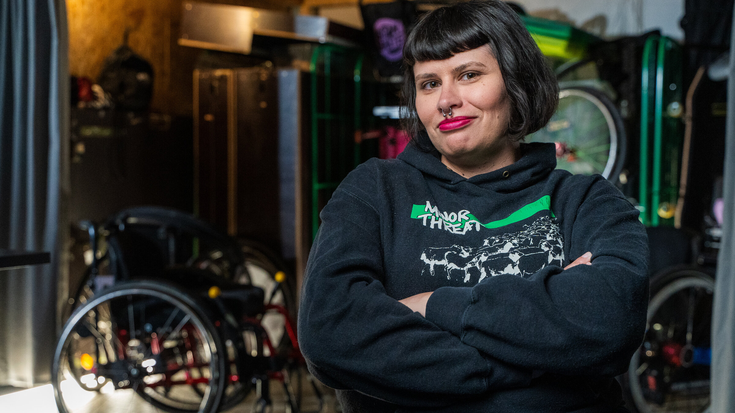 "Einfach Mensch - Erfolg kennt keine Barrieren": Die Protagonistin Lisa Lebuser sitzt in einem Raum und schaut lächelnd in die Kamera. Im Hintergrund stehen mehrere Rollstühle.