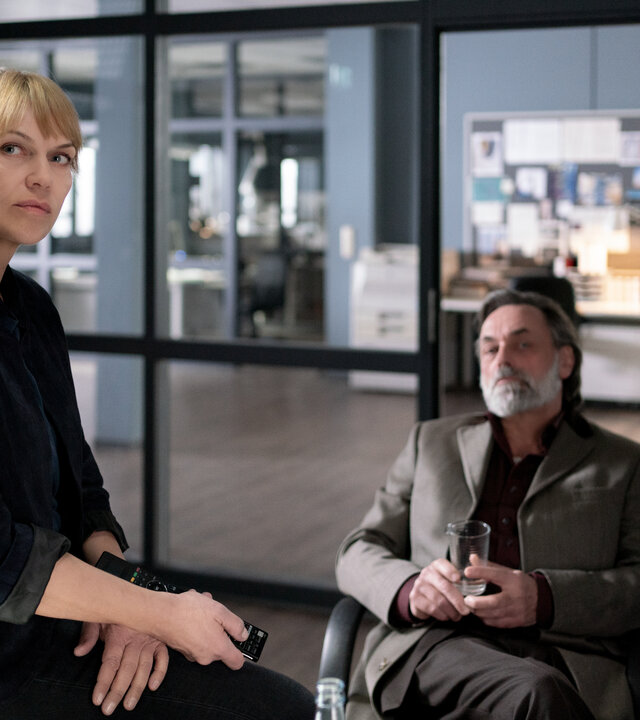 "Helen Dorn - Der deutsche Sizilianer": Toni Vizzante (Peter Benedict) sitzt in Helen Dorns (Anna Loos) Büro. Sie sitzt auf der Schreibtischkante.