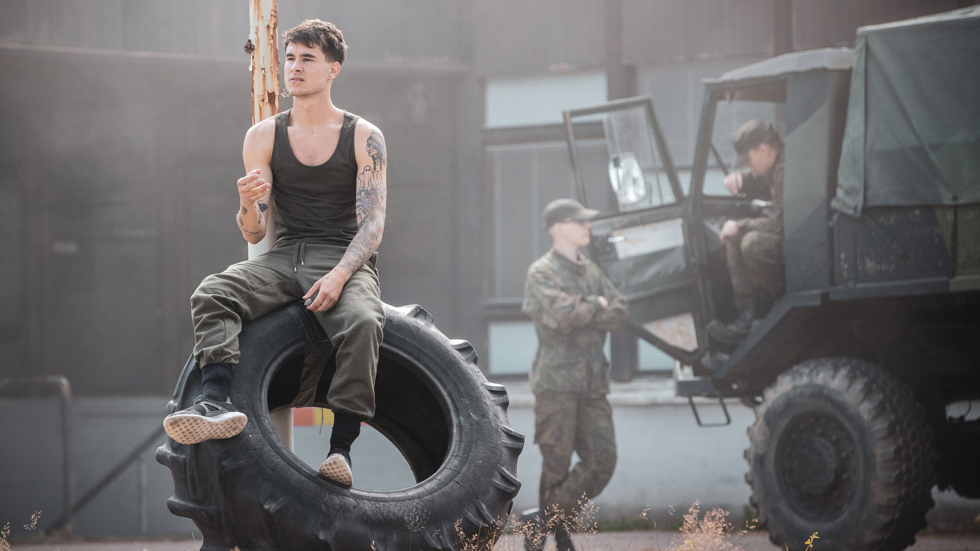 "Californian Commando - Der Schutzengel": Van (Kian Lawley) sitzt auf einem Reifen und schaut nachdenklich zur Seite.