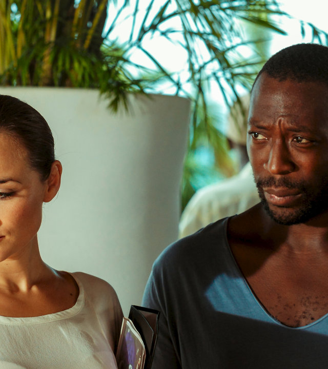 "Death in Paradise: Der 3-Uhr-Tee": Anna Jones (Emma Pierson) und Paul Vincent (Shaun Parkes) stehen nebeneinander. Anna Jones schaut traurig nach unten, und Paul Vincent sieht besorgt zur Seite.