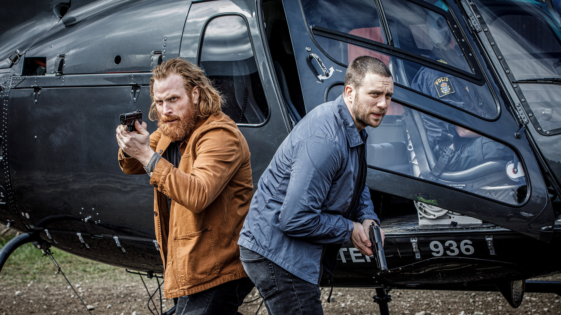 "Kommissar Beck: Ein neues Leben": Steinar Hovland (Kristofer Hivju) und Josef Eriksson (Martin Wallström) stehen mit gezogenen Waffen Rücken an Rücken vor einem Hubschrauber.