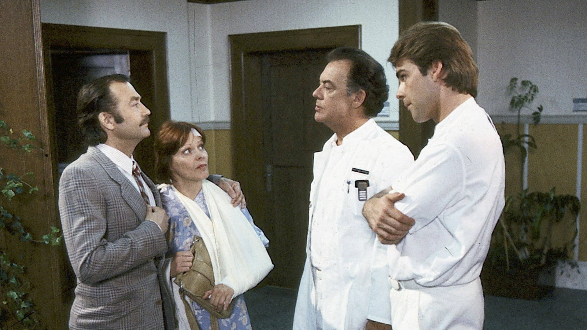 "Die Schwarzwaldklinik - Steinschlag": Konrad Pesch (Jürgen Schmidt) steht mit Gertrud Melldorf (Loni von Friedl) auf dem Krankenhausflur und spricht mit Klaus (Klausjürgen Wussow) und Udo Brinkmann (Sascha Hehn).