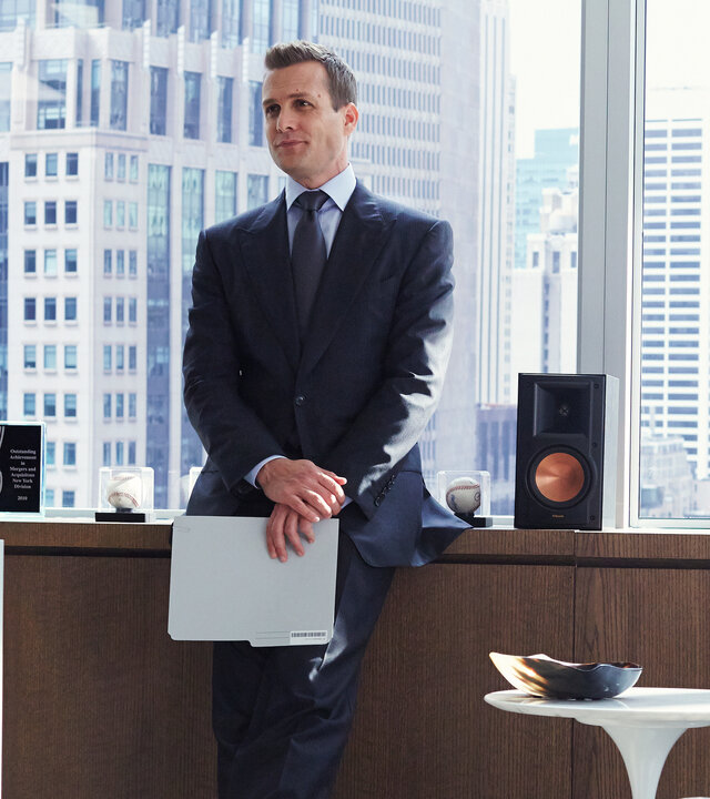 "Suits - Private Einsichten": Harvey (Gabriel Macht) steht im Anzug in einem Büro, lässig an ein Sideboard gelehnt. Hinter ihm sind große Fenster mit Blick auf die Skyline zu sehen.