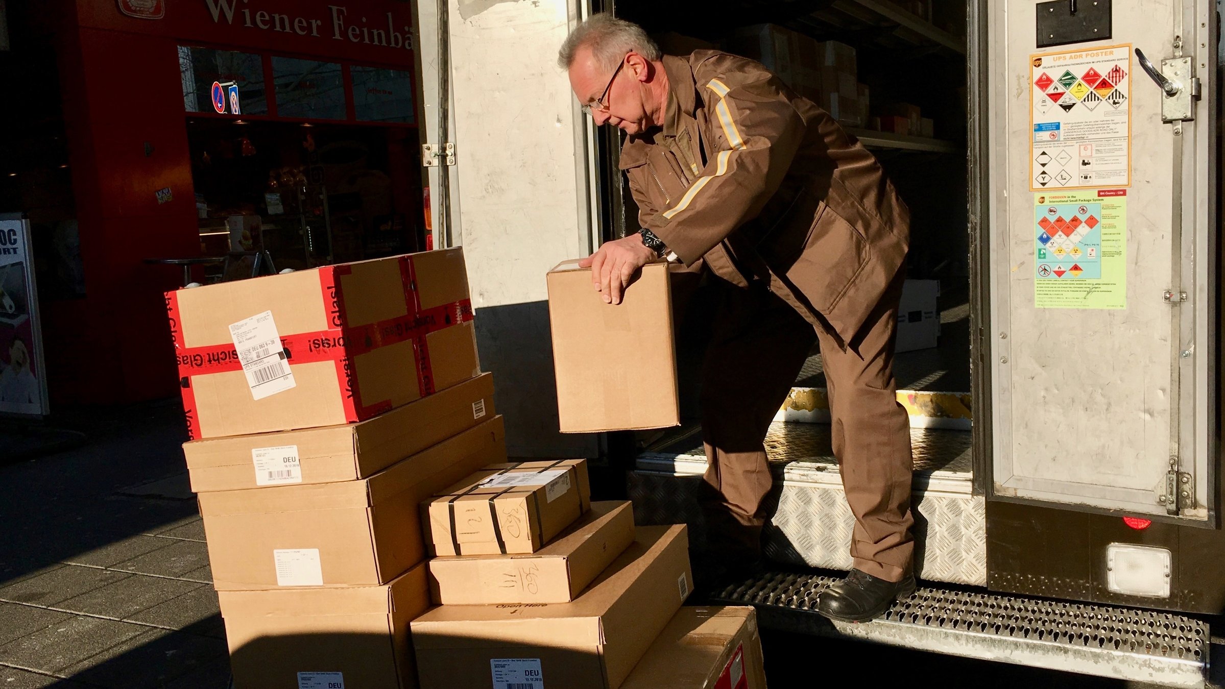 "37°: Ich pack'' das - Knochenjob Paketzusteller": Thomas steht im Lkw und lädt die Pakete auf einen Rollwagen, der vor ihm steht.