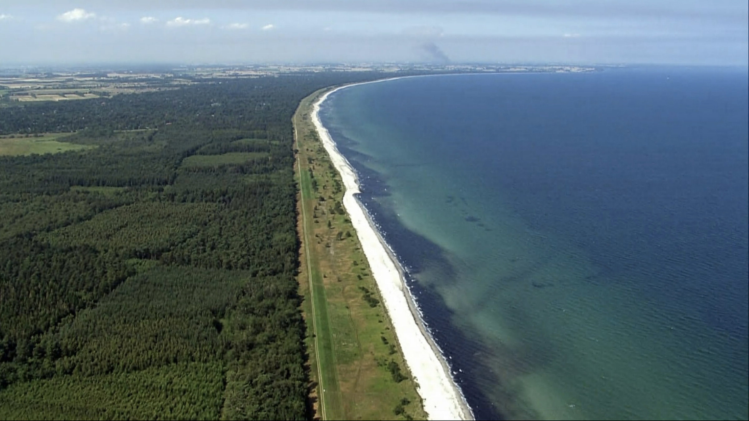 "Dänemark von oben": Ein langer Sandstrand und bewaldete Küste in Dänemark.
