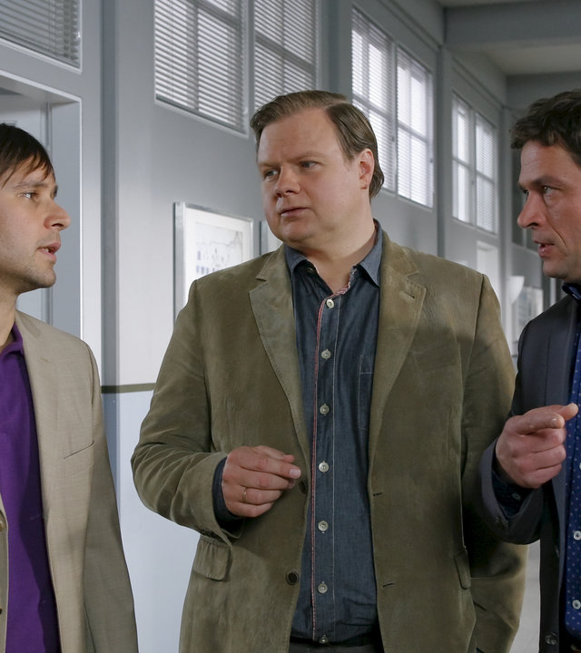 "Die Rosenheim-Cops - Sport ist Mord": Harald Singer (Atef Vogel), Kommissar Hartl (Michael A. Grimm) und Kommissar Lind (Tom Mikulla) stehen im Flur eines Gebäudes und reden.
