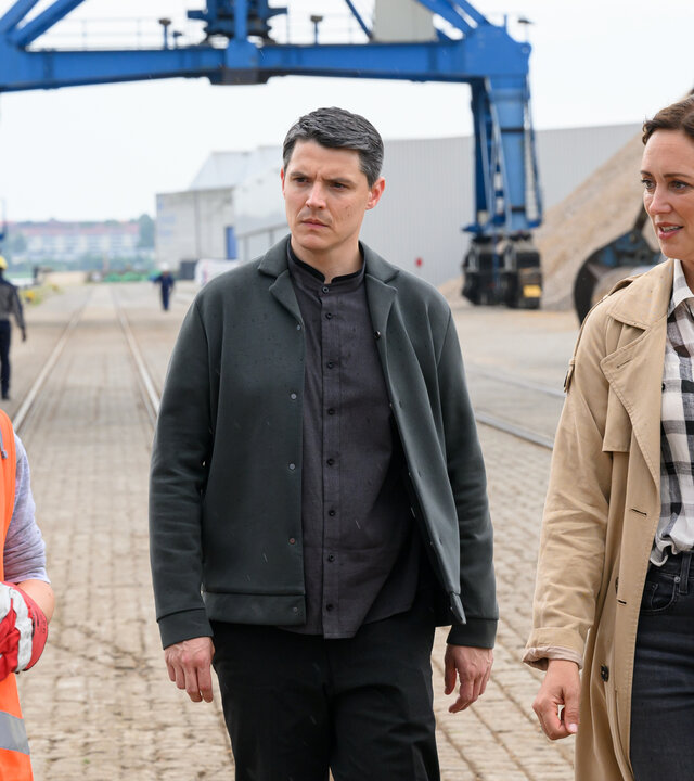 "SOKO Wismar – Die neun Gehirne des Oktopus": Kriminalkommissar Rico Sander (Benjamin Strecker) und Hauptkommissarin Karoline Joost (Nike Fuhrmann) befragen Kranfahrerin Nancy Dorn (Annette Strasser) auf ihrer Arbeitsstelle im Hafen.