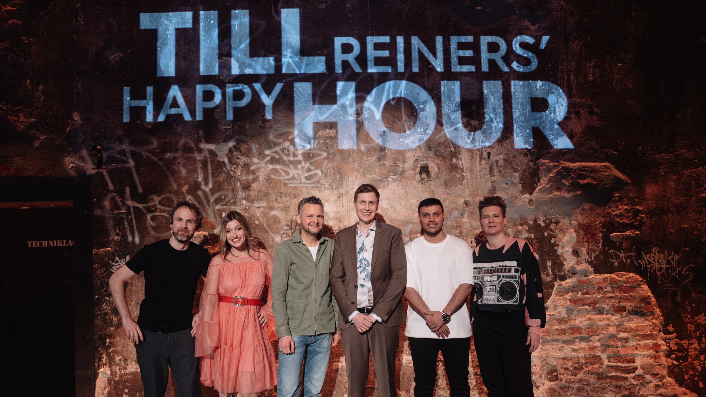 "Till Reiners' Happy Hour": Gruppenbild auf der Bühne vor dem Happy Hour Logo mit: Tino Bomelino, Malarina, Tobias Mann, Till Reiners, Osan Yaran und Kirsten Fuchs.