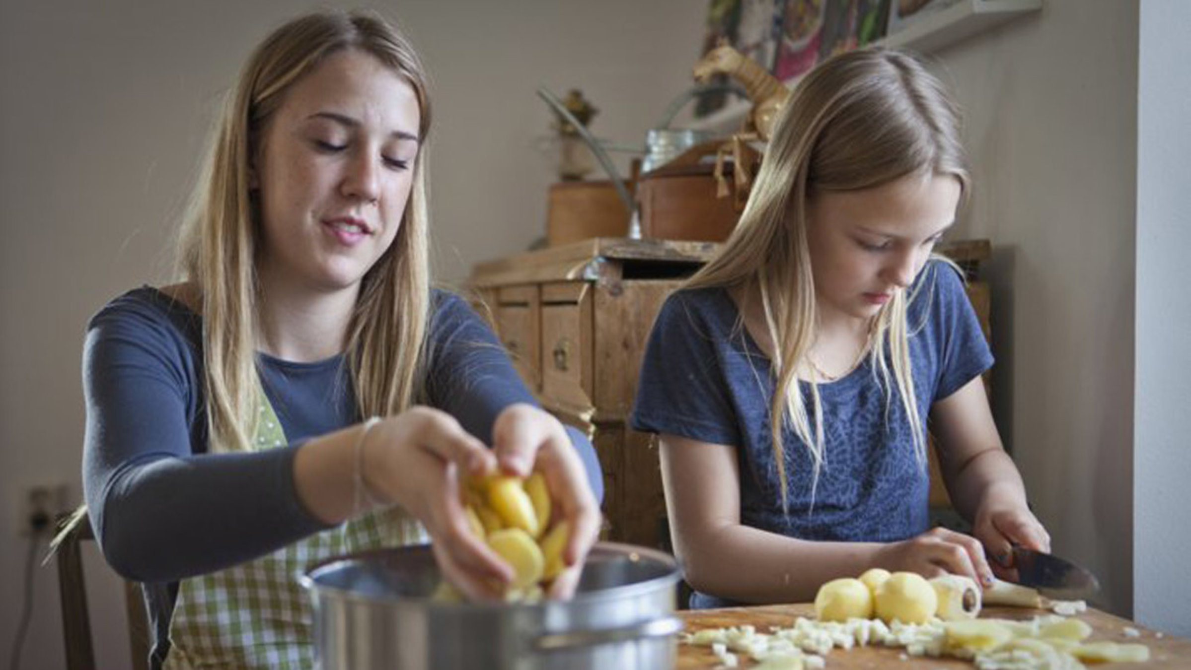 "Zu Tisch ... auf Gotland": Pauline und Philippa Granlund sitzen an einem Tisch und schälen Kartoffeln.