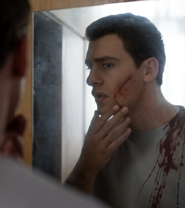 "Füxe - Ich bin der, der ich bin": Adem (Valon Krasniqi) betrachtet die blutende Wunde auf seiner linken Wange im Spiegel. Sein T-Shirt ist mit Blut bespritzt.