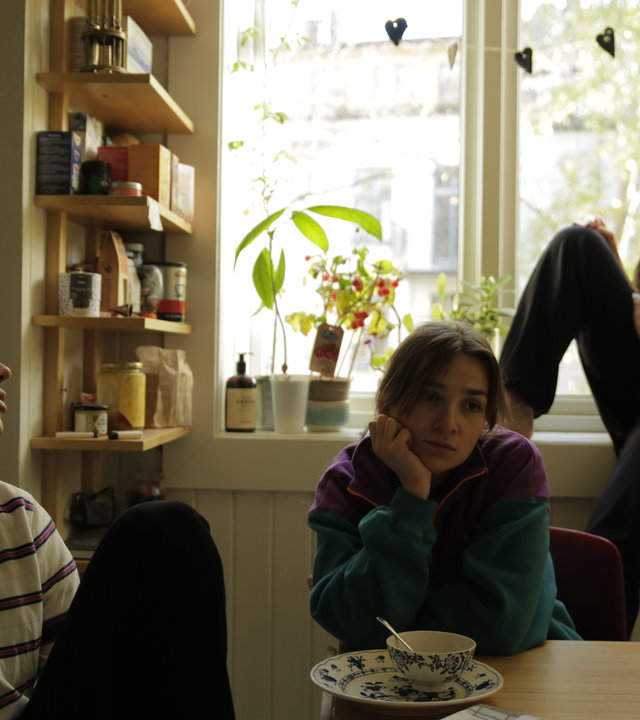 "About Saturday - Red mit mir": Lotte (Hanna Heider Hov), Klara (Darin Hagi) und Mo (Kayd Wacays) sitzen zusammen im Esszimmer. Während Lotte verträumt an der Fensterbank lehnt, sitzen Mo und Klara am Esstisch und schauen trübselig drein.