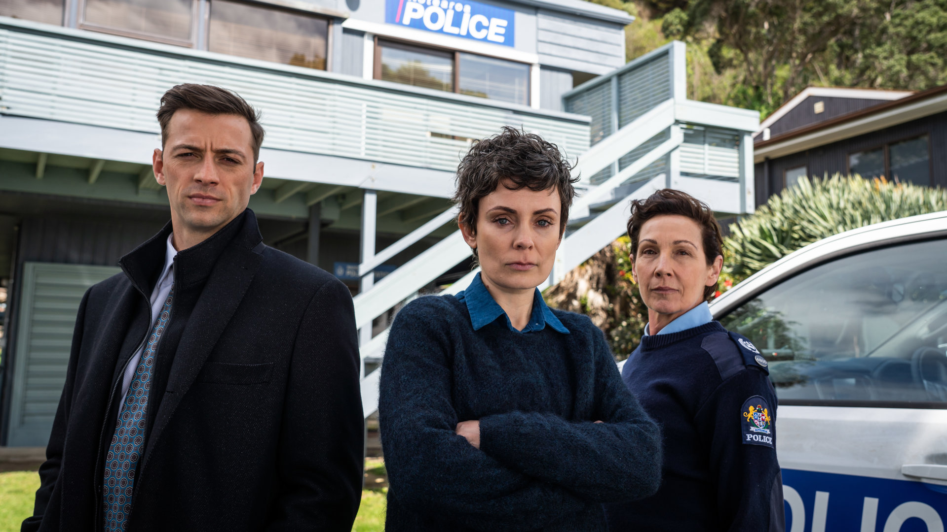 "Auckland Detectives  - Tödliche Bucht: Regenbogenwelt": Detective Senior Sergeant Jessica Savage (Kate Elliott), ihr Kollege Detective Sergeant Justin Harding (Ido Drent) und Senior Sergeant Denise Abernethy (Alison Bruce) stehen vor der Polizeistation von Waiheke.