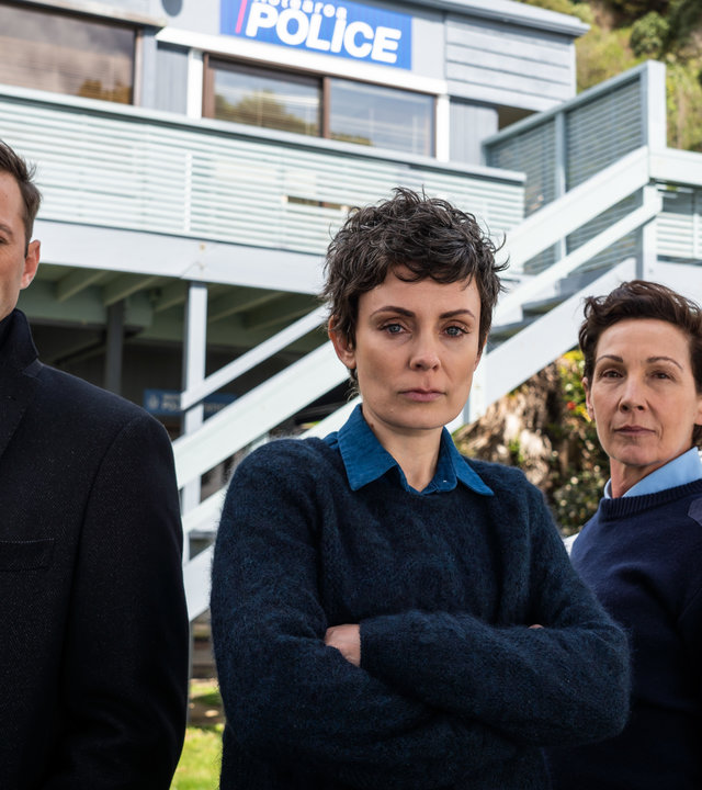 "Auckland Detectives  - Tödliche Bucht: Regenbogenwelt": Detective Senior Sergeant Jessica Savage (Kate Elliott), ihr Kollege Detective Sergeant Justin Harding (Ido Drent) und Senior Sergeant Denise Abernethy (Alison Bruce) stehen vor der Polizeistation von Waiheke.