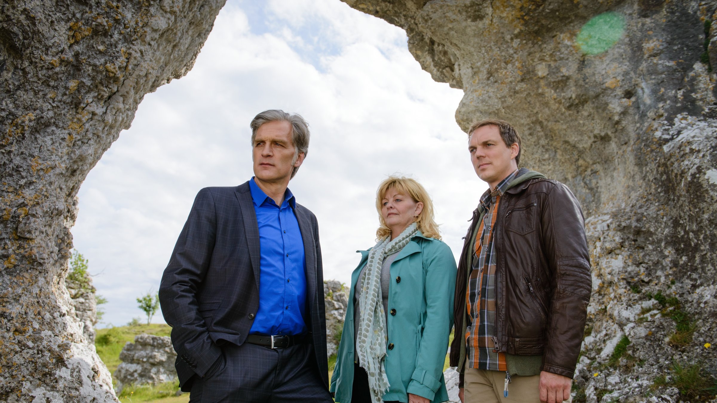"Der Kommissar und das Meer - Der böse Mann": Robert Anders (Walter Sittler), Ewa Svensson (Inger Nilsson) und Thomas Wittberg (Andy Gätjen) stehen vor einer Felsöffnung und schauen alle in eine Richtung.