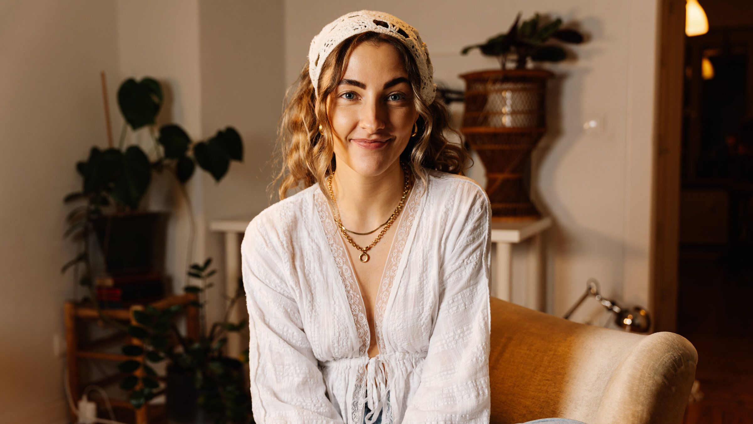 "37° Leben: PHASE: Eigentlich alles okay": Lisa, eine junge Frau, sitzt im Schneidersitz auf einem beigen Sessel und schaut lächelnd in die Kamera.