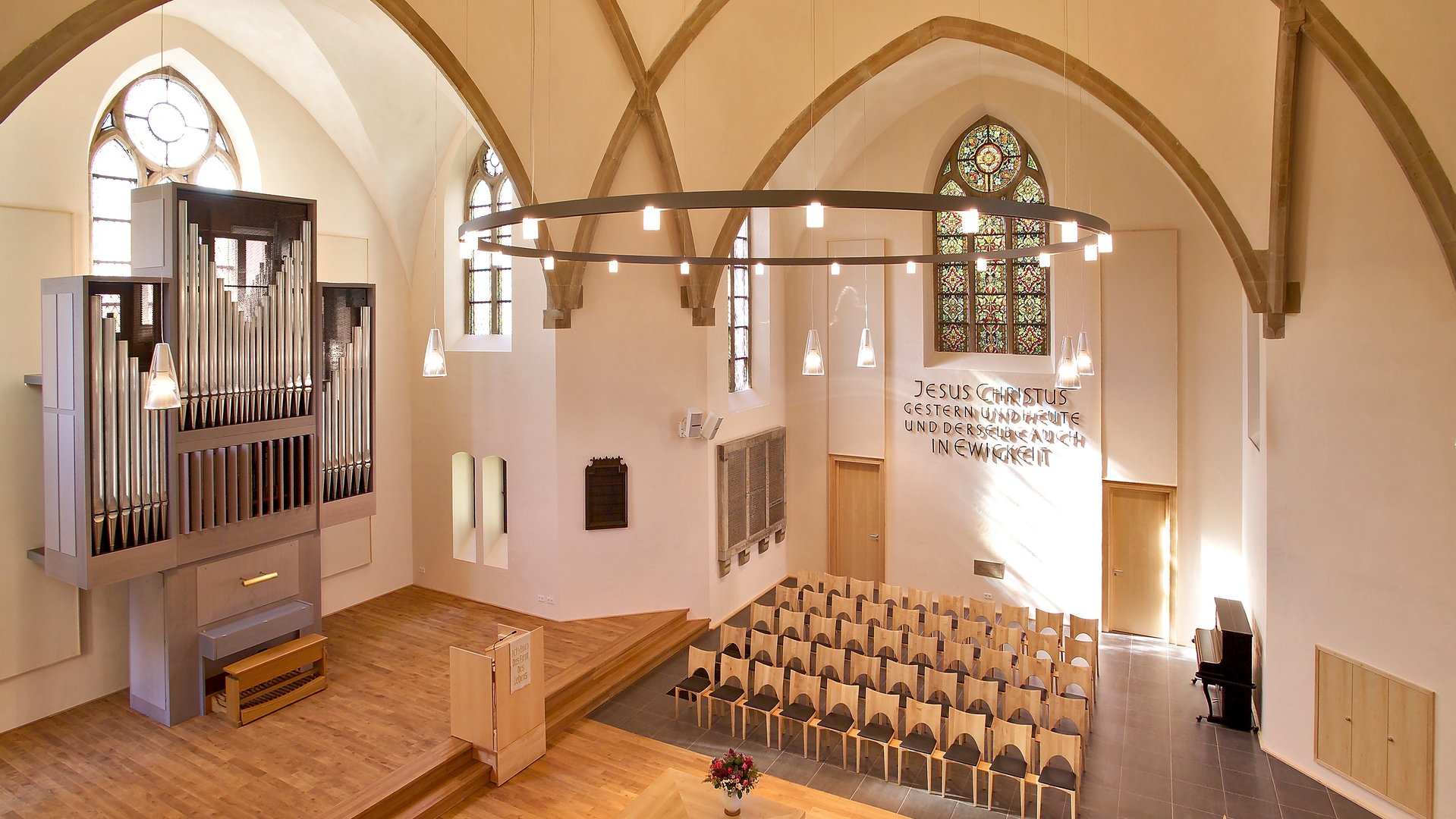 "Evangelischer Gottesdienst - Das Fest beginnt": Blick von schräg oben in das modern und schlicht gehaltene Innere der Petri-Kirche in Herford. Der Boden und das Gestühl sind aus hellem Holz, die modern aussehende Orgel ist hellgrau.