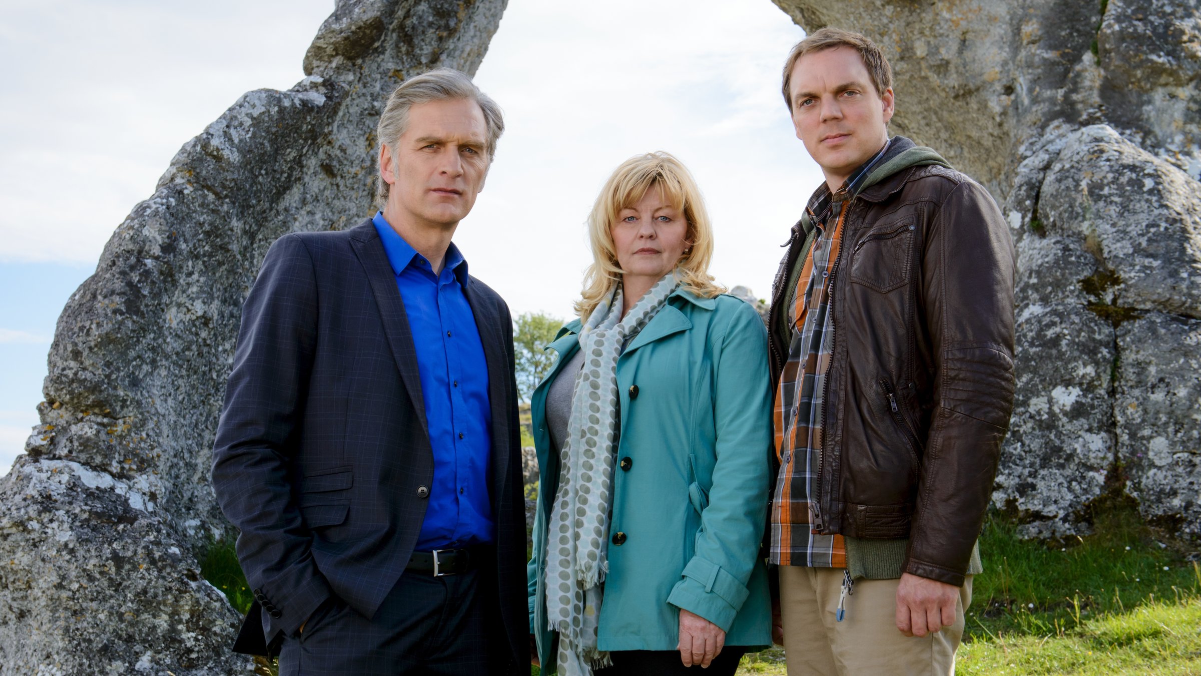 "Der Kommissar und das Meer - In einer dunklen Nacht": Robert Anders (Walter Sittler), Ewa Svensson (Inger Nilsson), Thomas Wittberg (Andy Gätjen) stehen nebeneinander vor einer Felsformation und schauen in die Kamera.