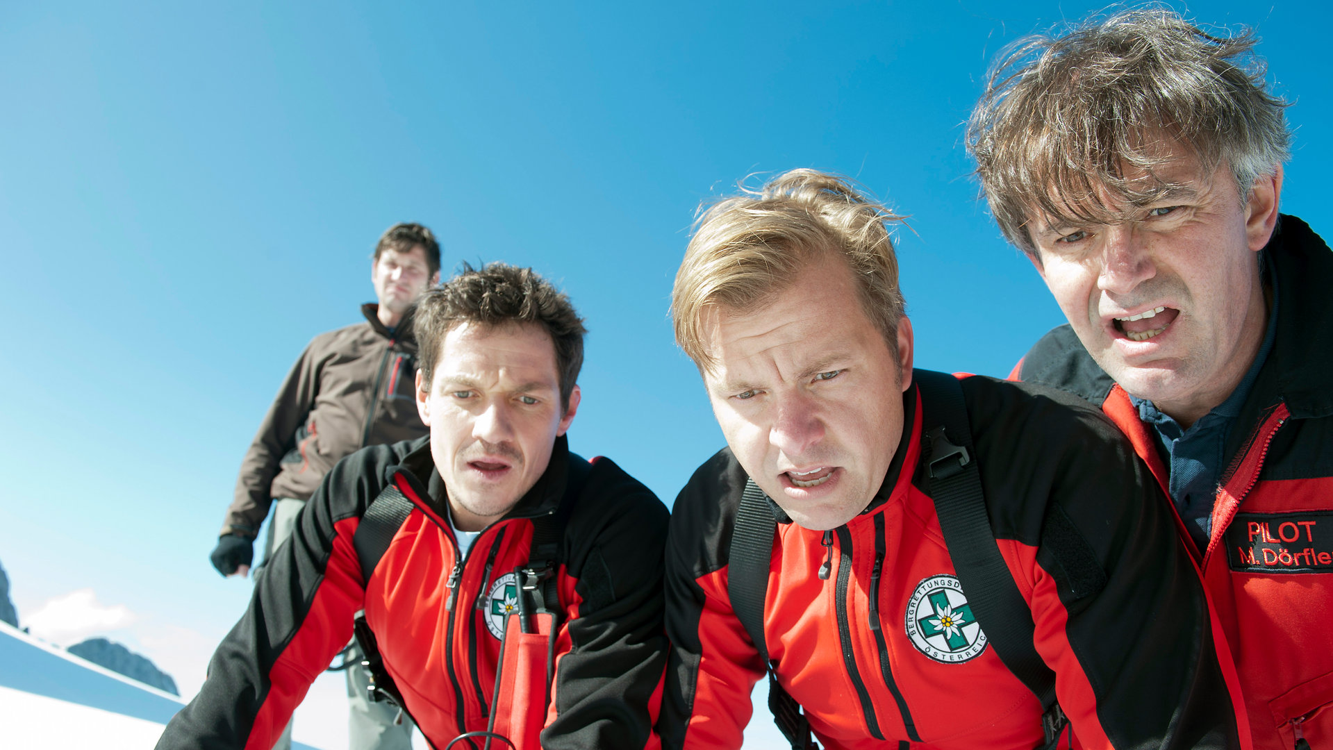 "Die Bergretter: Tödliches Vertrauen - Teil 1": Die Bergretter Tobias (Markus Brandl), Toni (Martin Klempnow) und Michael (Robert Lohr) schauen mit entsetzten Gesichtern in eine Felsspalte hinab. Hinter ihnen steht Hans Baumann (Andreas Kiendl) und beobachtet die Szene.