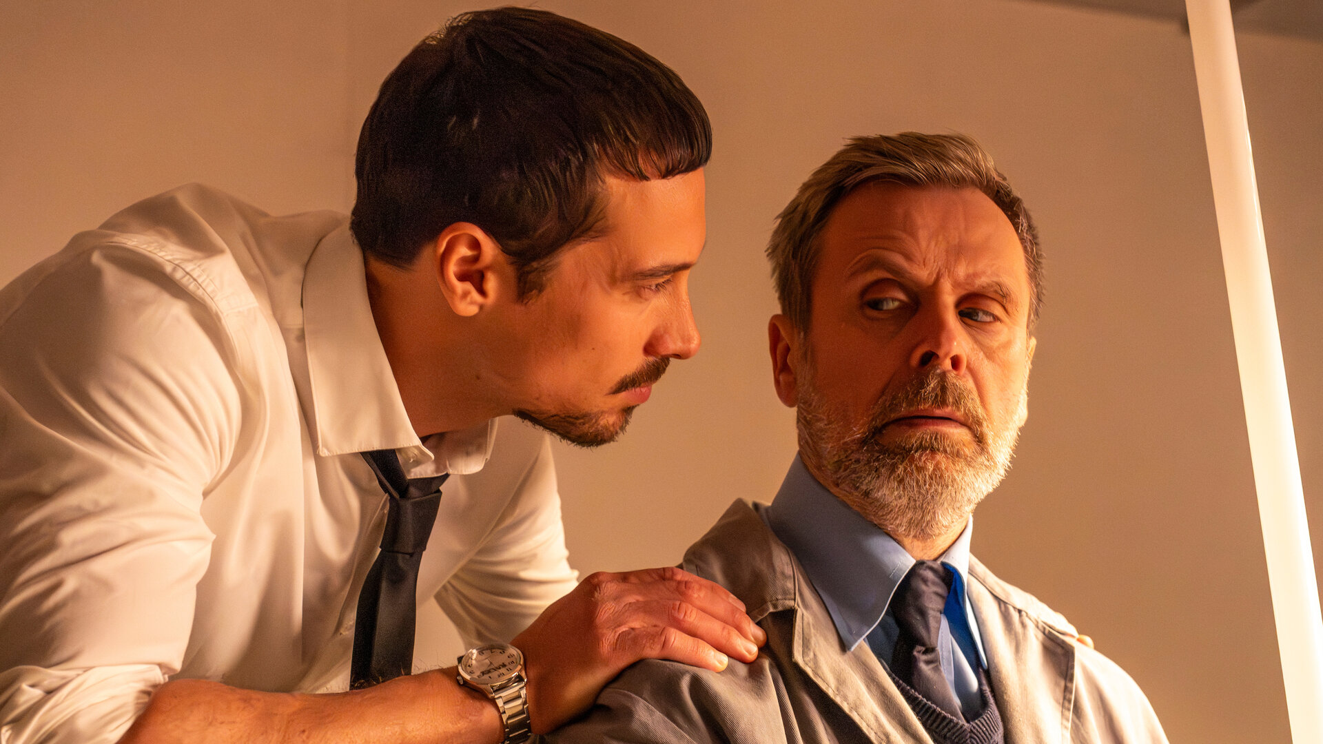 "SPYON - Die Lizenz zum Grillen": In einem Innenraum: Andreas (Klaus Steinbacher) steht hinter Hausmeister Harald (Matthias Matschke) und blickt zu ihm. Hausmeister Harald blickt seitlich über seine Schulter zu Andreas.