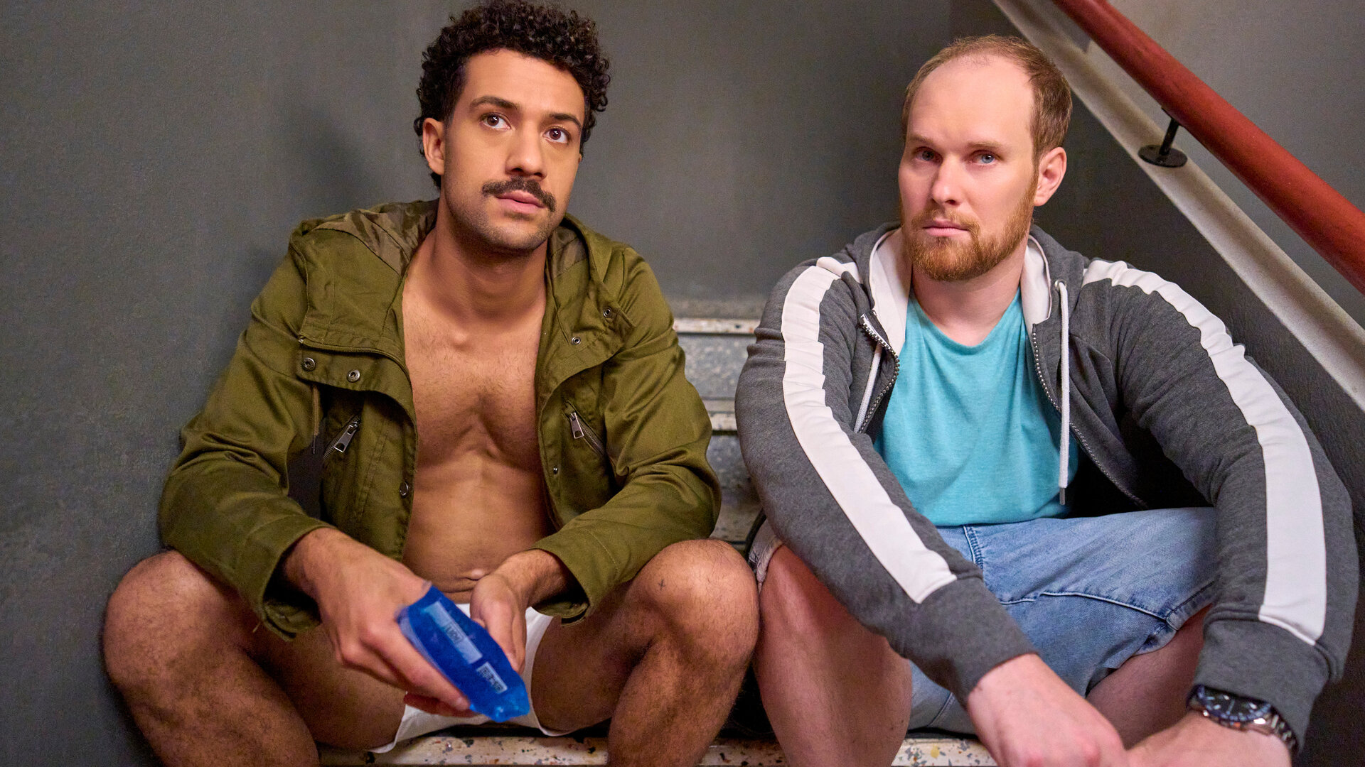 "Ich dich auch! - Die Aubergine": Yannik (Rojan Juan Barani) sitzt zusammen mit Sven (Sven Daniel Bühler) im Treppenhaus. Beide schauen sehr ernst.