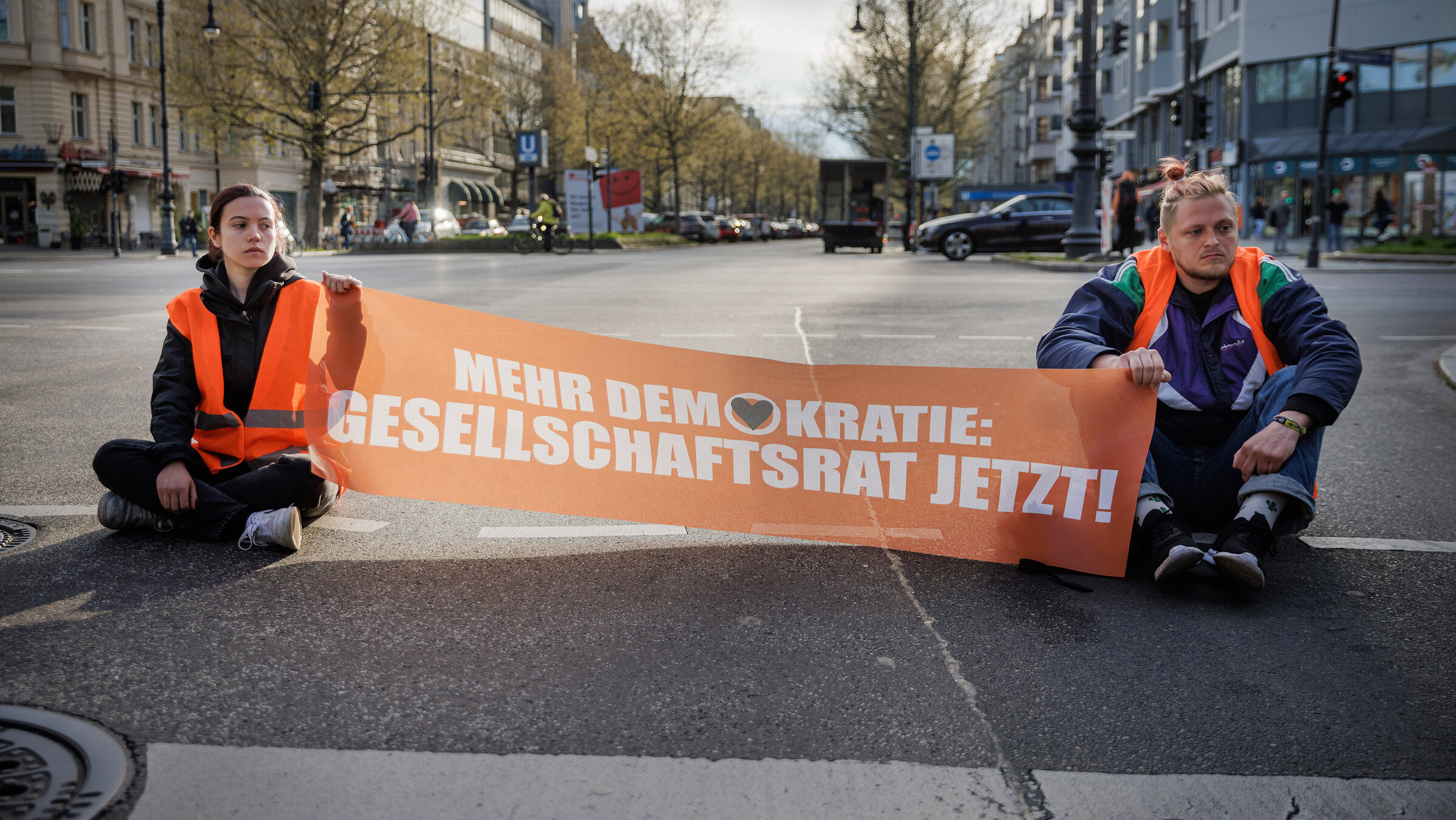 "Radikal fürs Klima: Helden oder Kriminelle?": Straßenblockade durch Aktivisten der "letzten Generation" auf dem Kurfürstendamm in Berlin.